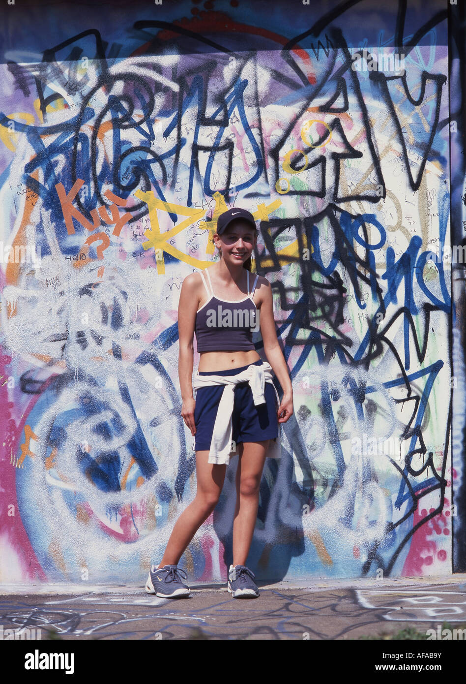 Junge Teenager-Mädchen indem Sie sich durch Graffiti Wand, Berkshire, England, Vereinigtes Königreich Stockfoto