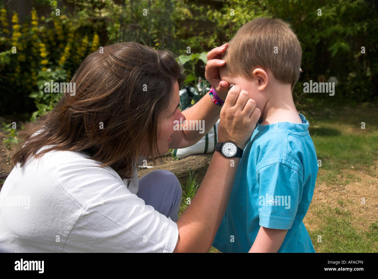 Mutter überprüfen und entfernen eine Fliege von einem kleinen Jungen s Auge Stockfoto