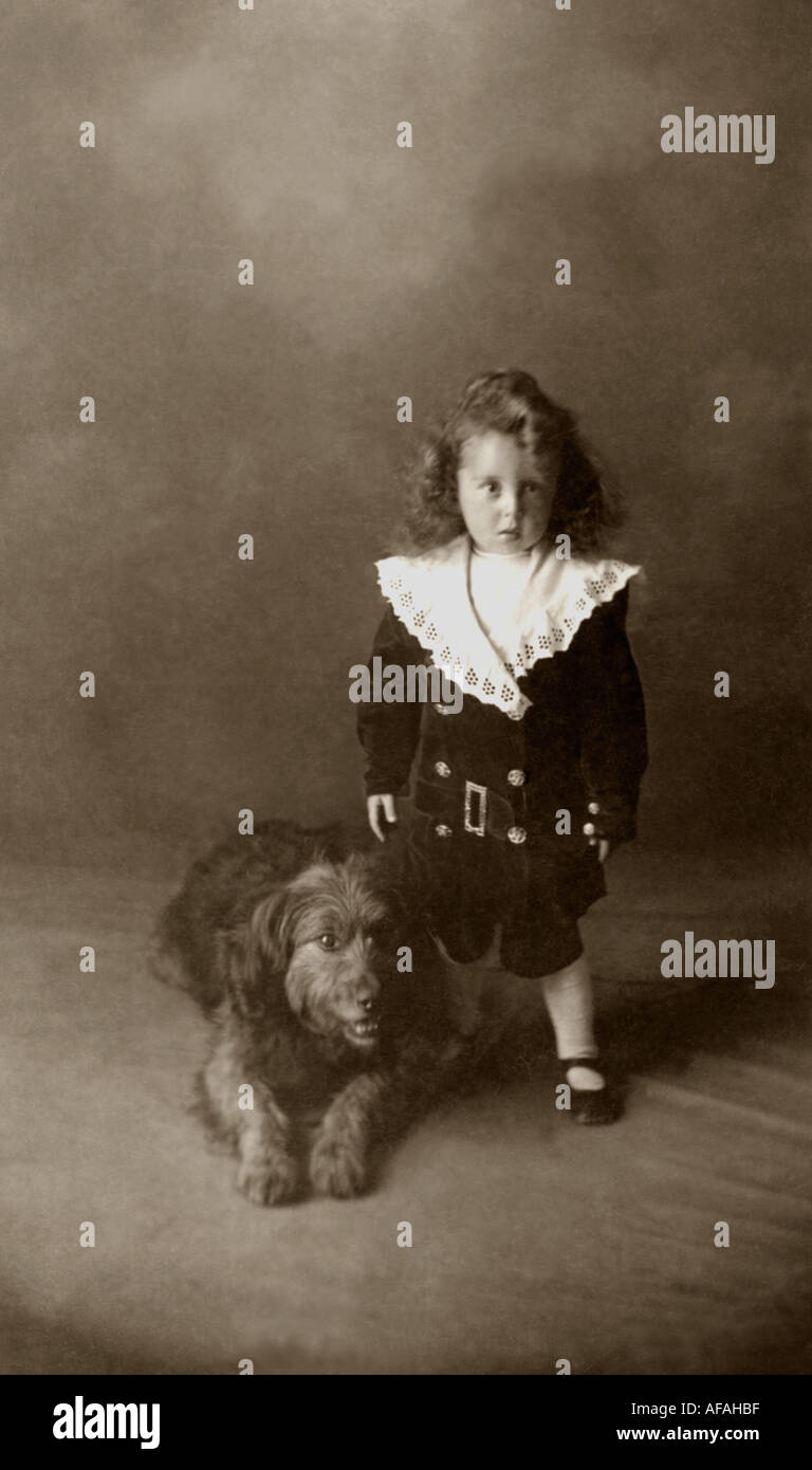Studioporträt eines edwardianischen Jungen mit einem Haustier, der einen modischen Anzug im Typ „Little Lord Fauntleroy“ mit großem Spitzenkragen trägt, um 1910, Großbritannien Stockfoto