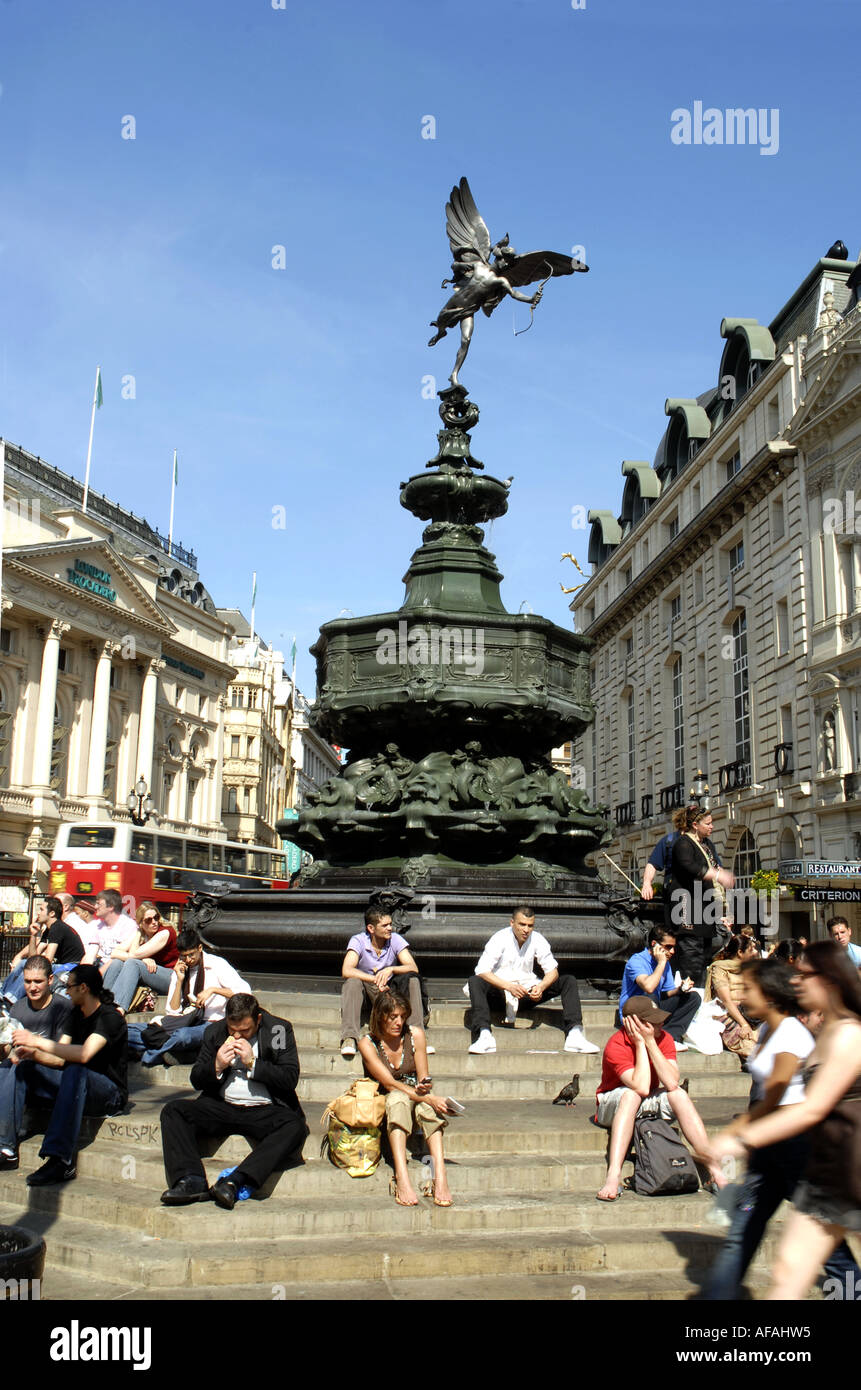 Touristen sitzen auf den Stufen rund um die Bronze Statue des Eros, Piccadilly Cicus, London, England. 1893 errichtete Denkmal Stockfoto