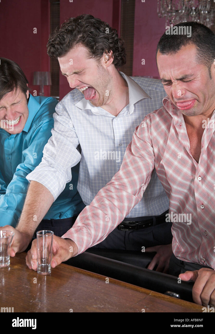 Gruppe von drei Freunden macht Grimassen nachdem er harte Getränke Stockfoto