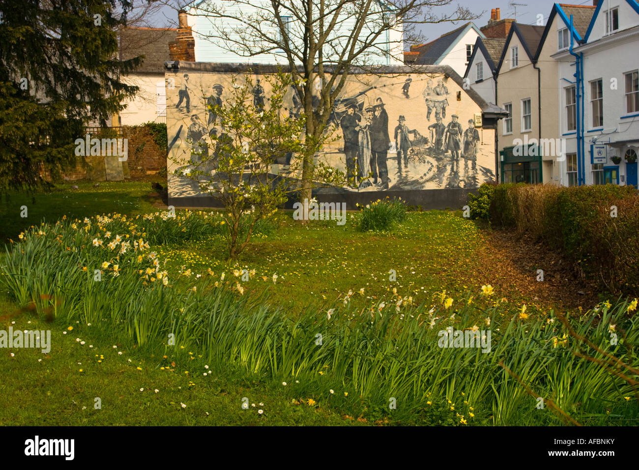 Blumen in Topsham Devon UK mit einem Wandbild Darstellung Lachsfischen am Fluss Exe im Hintergrund Stockfoto
