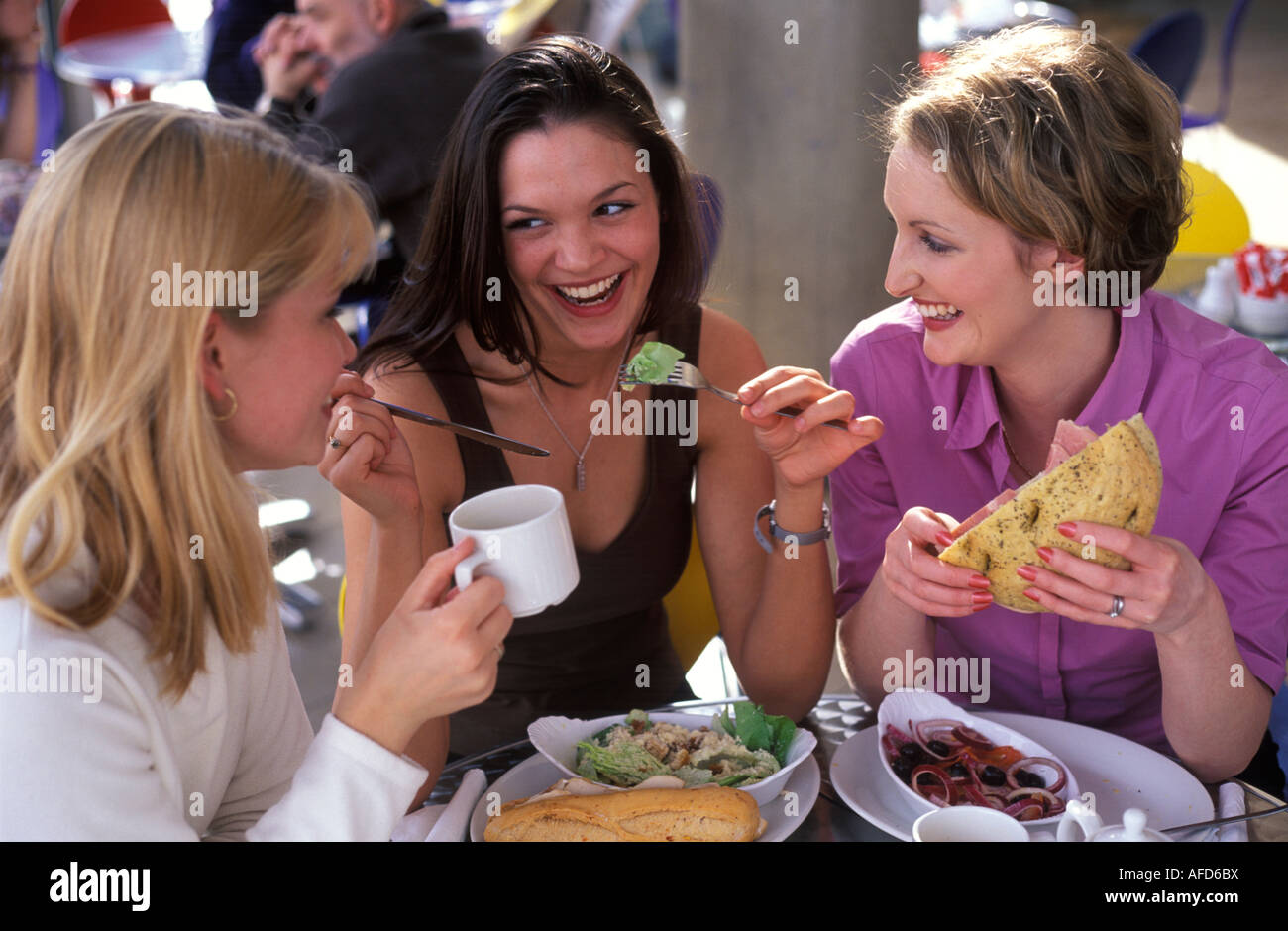 3 junge Frauen, die eine gesunde Mahlzeit in einem Restaurant teilen Stockfoto