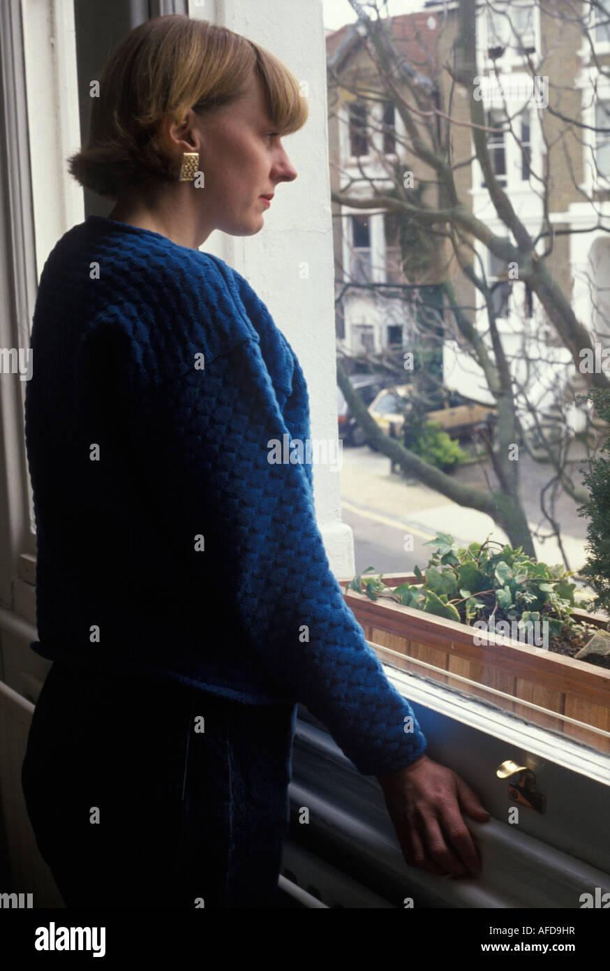 Frau stehend launenhaft am Fenster Stockfoto