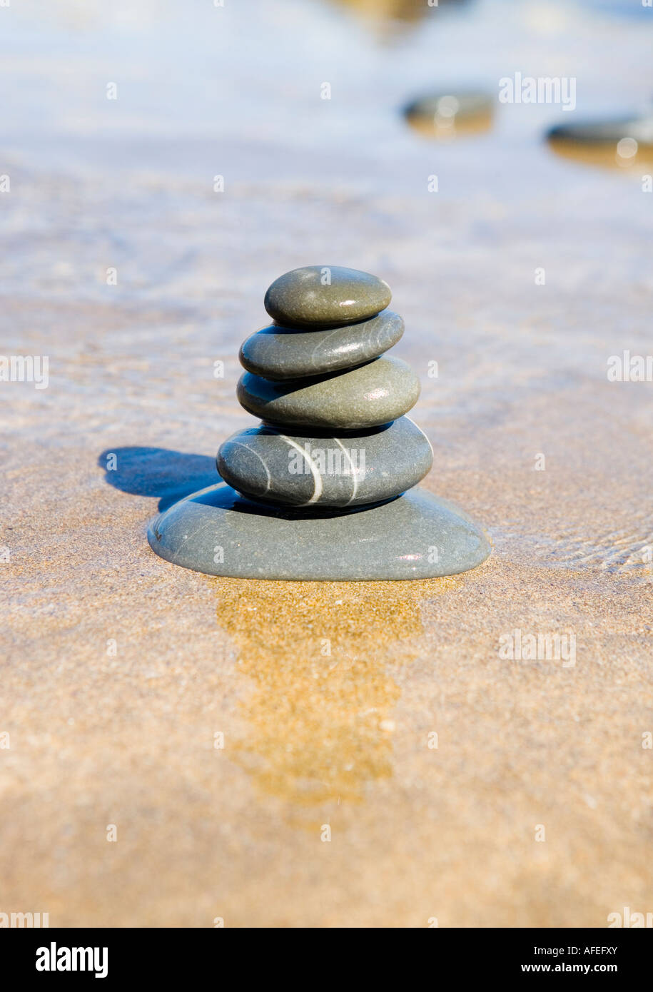 Graue Steinhaufen, balancieren auf einem Sandstrand Stockfoto