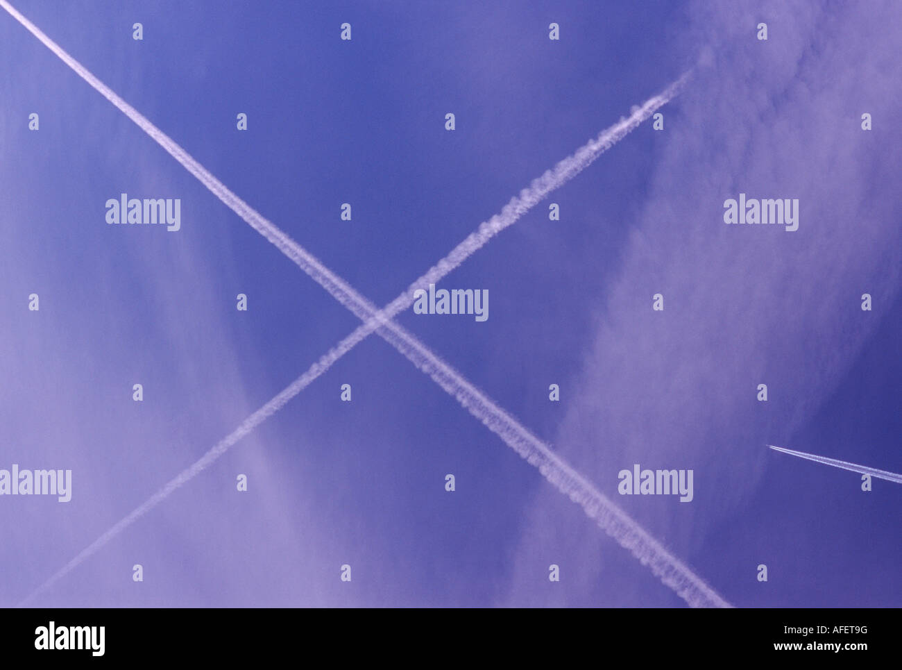 Ziel 1: Jet konvergierenden am Schnittpunkt von zwei weißen Kondensstreifen bilden ein X vor einem blauen Himmel. Stockfoto