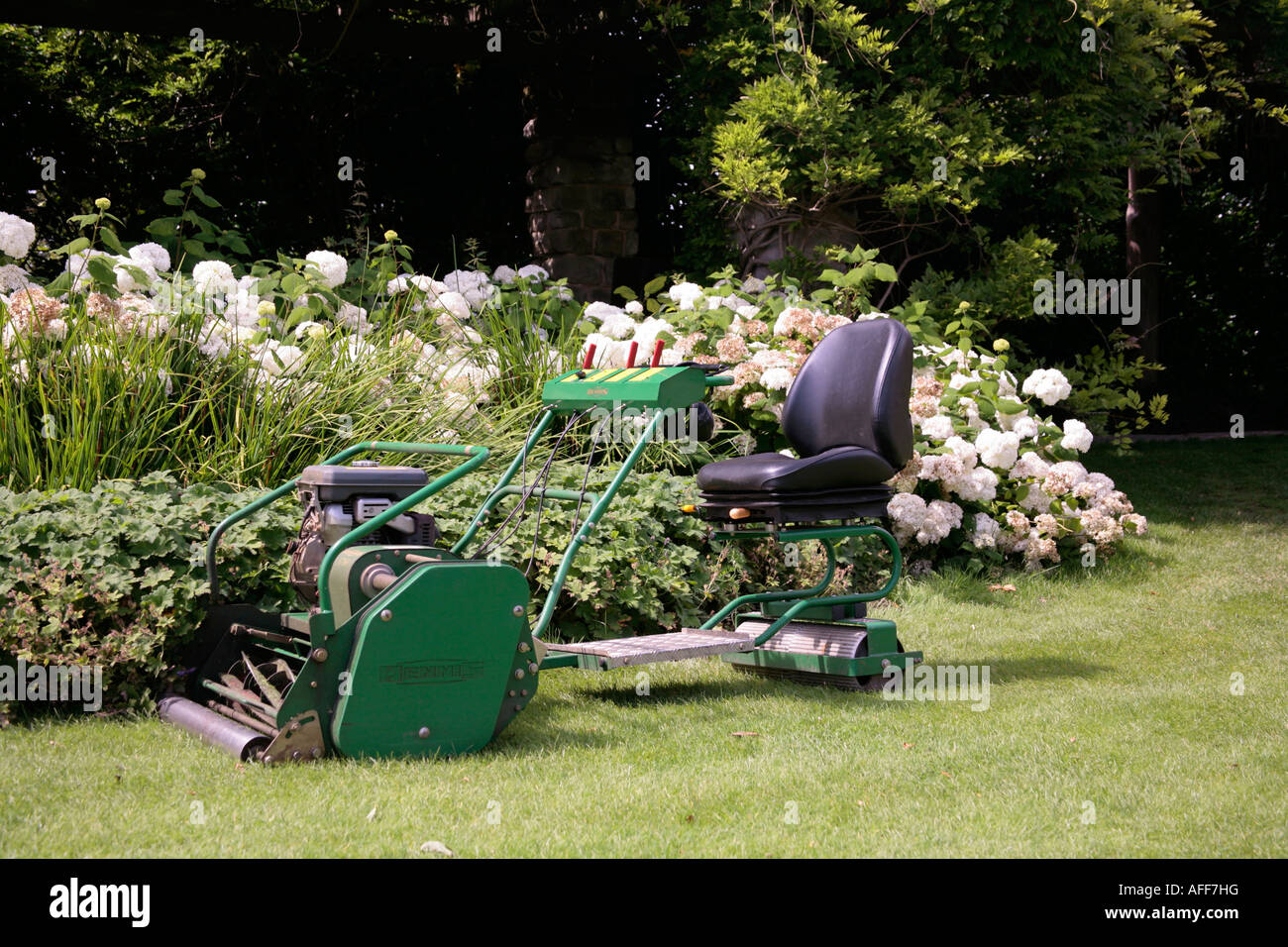 Ein Dennis fährt auf einem Rasenmäher in einem englischen Garten Stockfoto