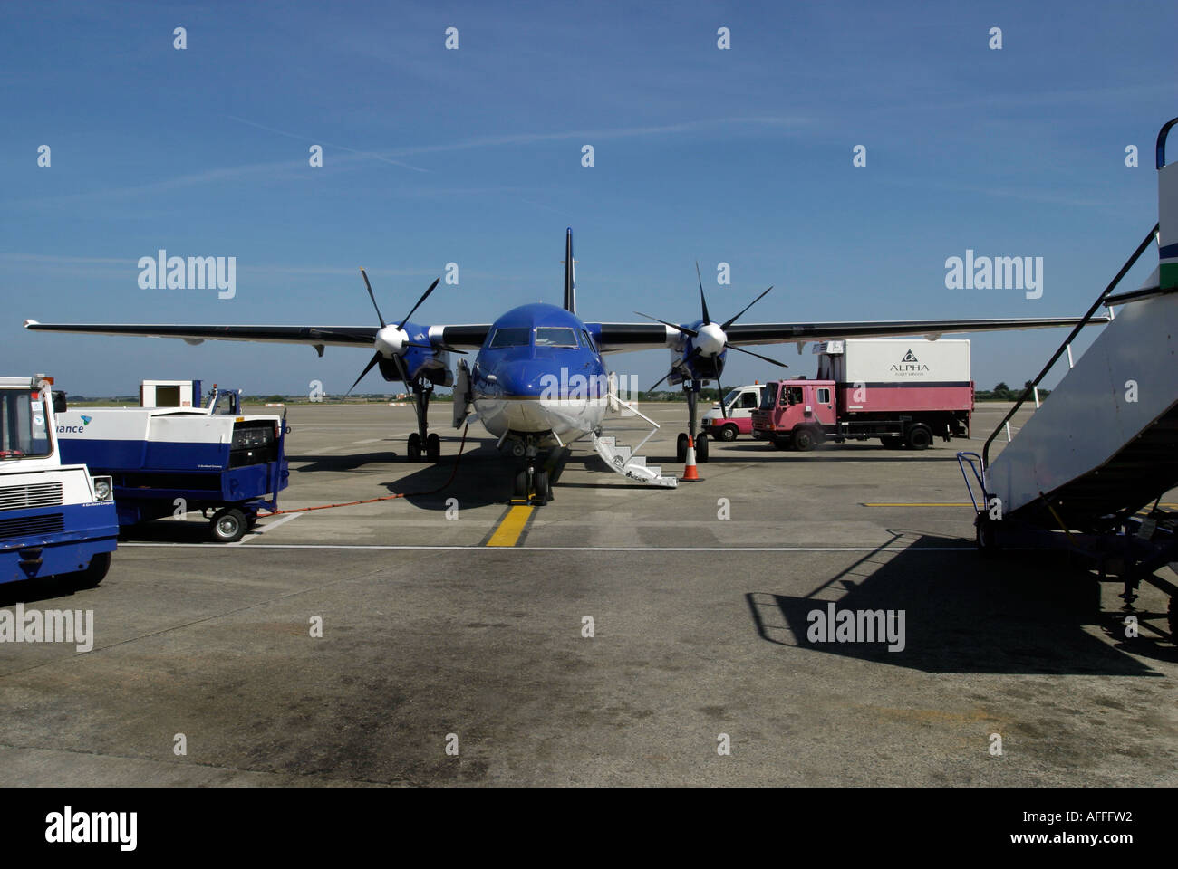 KLM-Propeller-Flugzeug auf dem Stand mit Alpha catering Fahrzeug und andere Begleitfahrzeuge in Anwesenheit Stockfoto