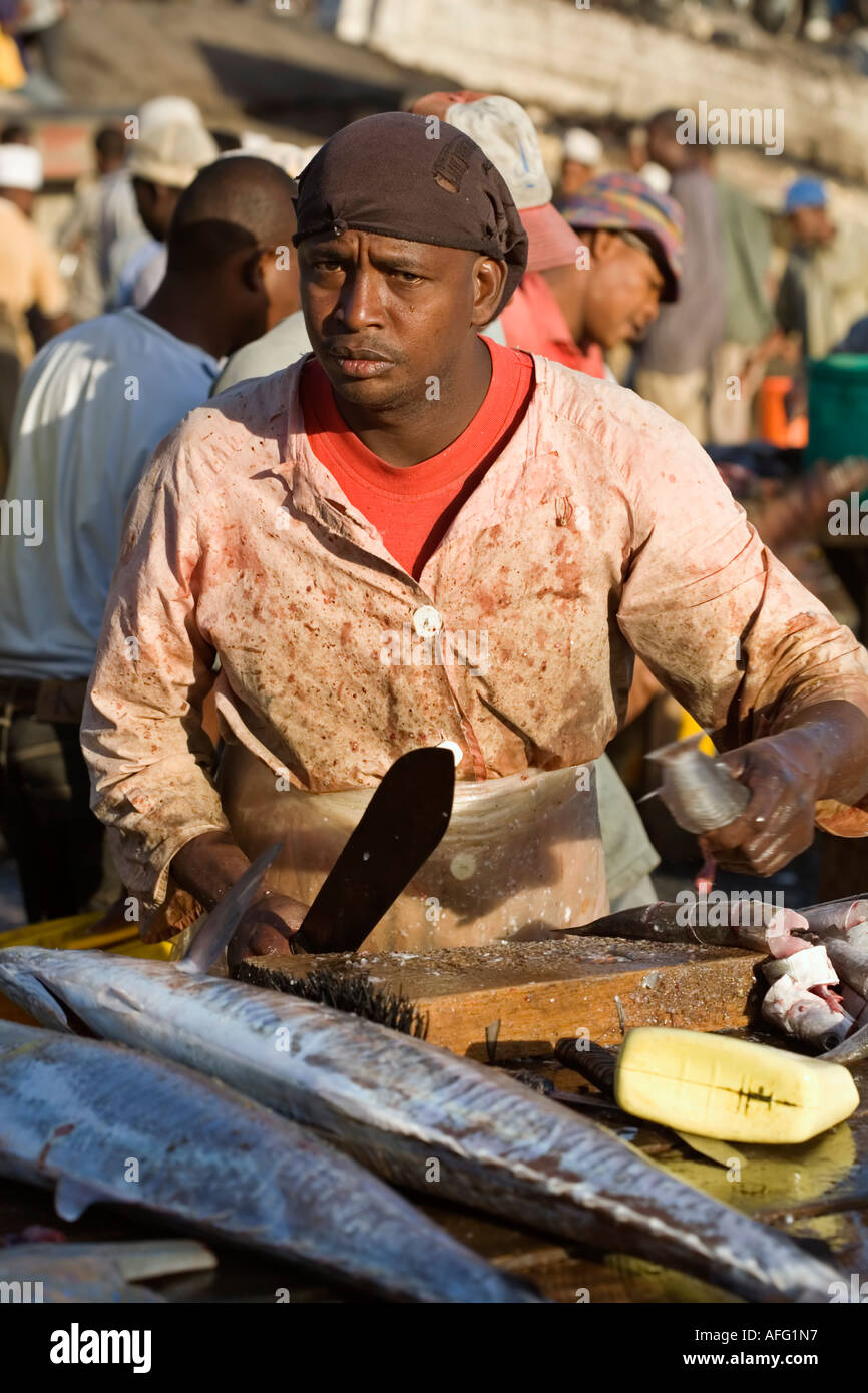 Mann in traditioneller Kleidung, die Zubereitung von Fisch zu verkaufen in Stone Town Fish Market, Zanzibar Stockfoto