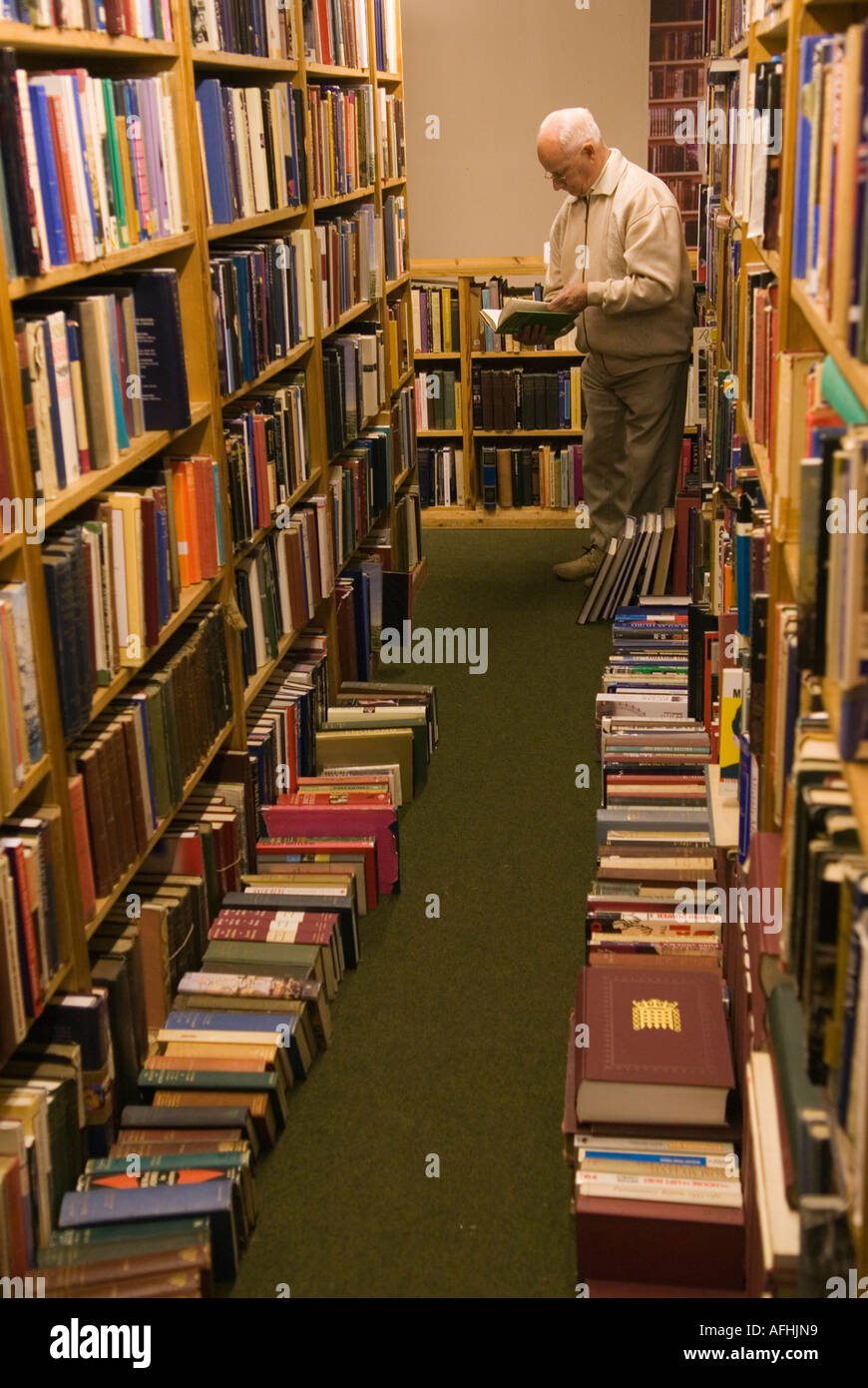 Hay Cinema Bookshop, Mann liest sich alte Bücher aus zweiter Hand. Volle Bücherregale Bücher liegen auf dem Boden. Hay-on-Wye Festival UK 2006 2000s Stockfoto