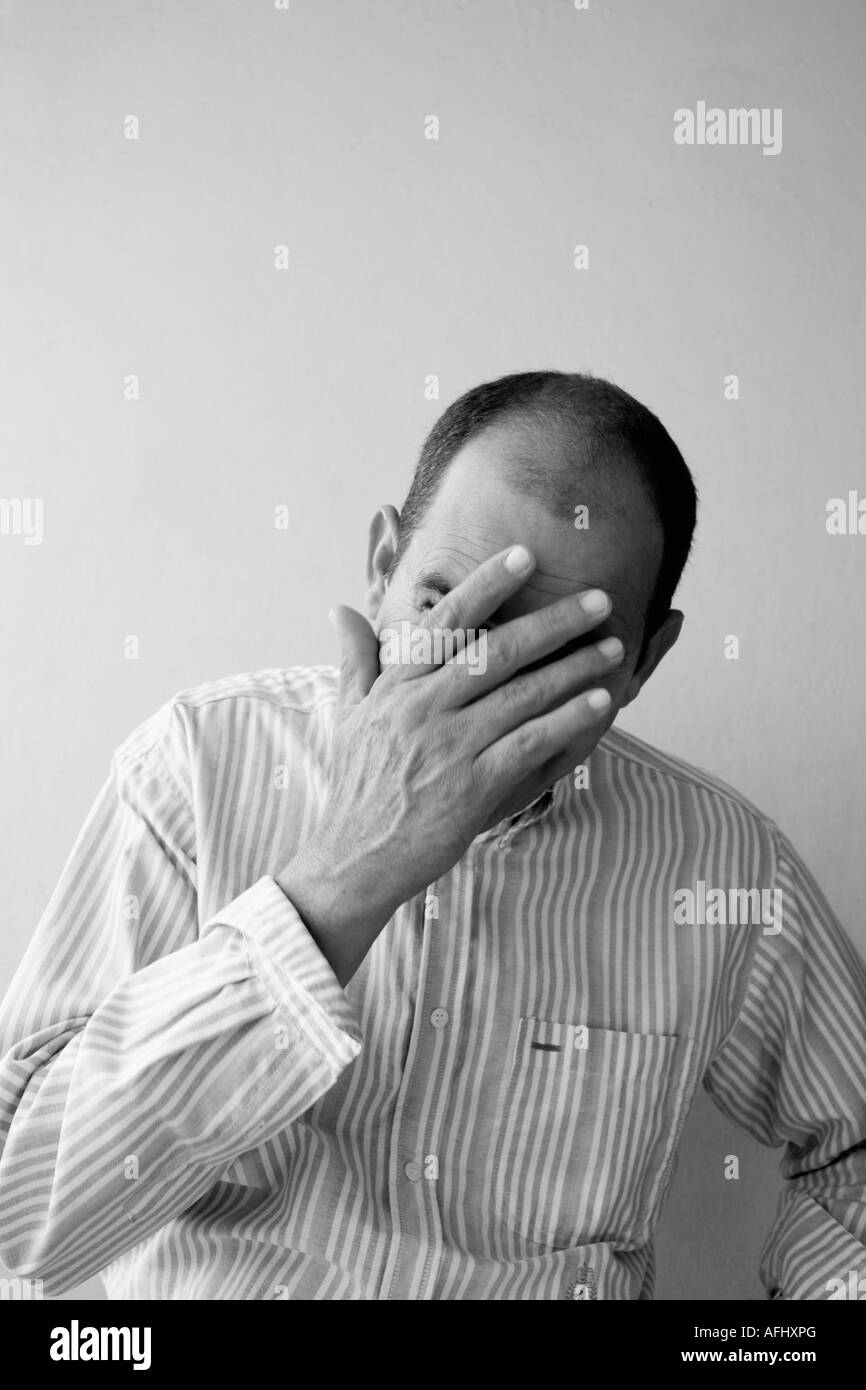 Reifer Mann versteckt sein Gesicht mit der hand Stockfoto