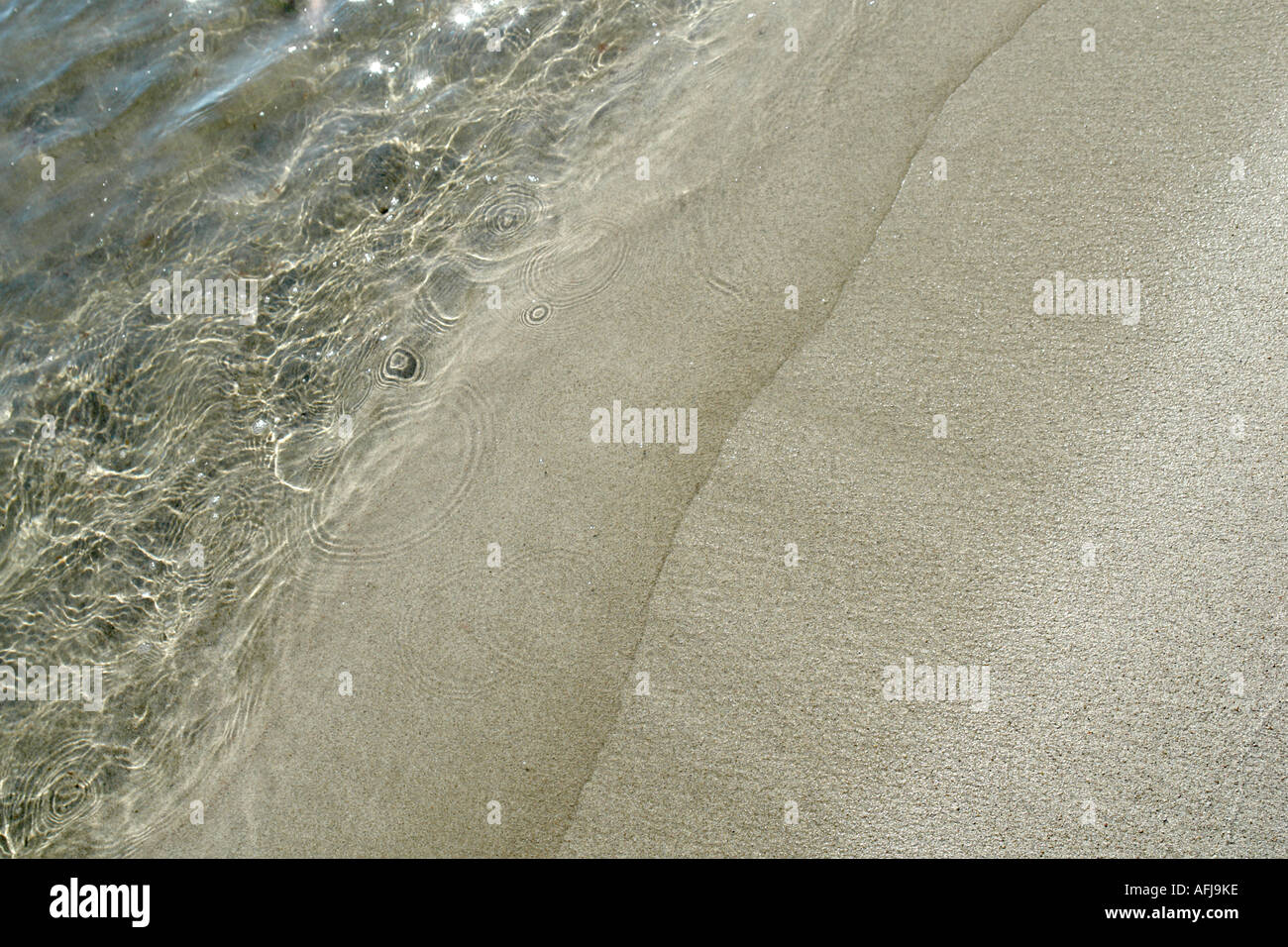 Wavelets an einem sandigen Strand auf Ibiza. Stockfoto