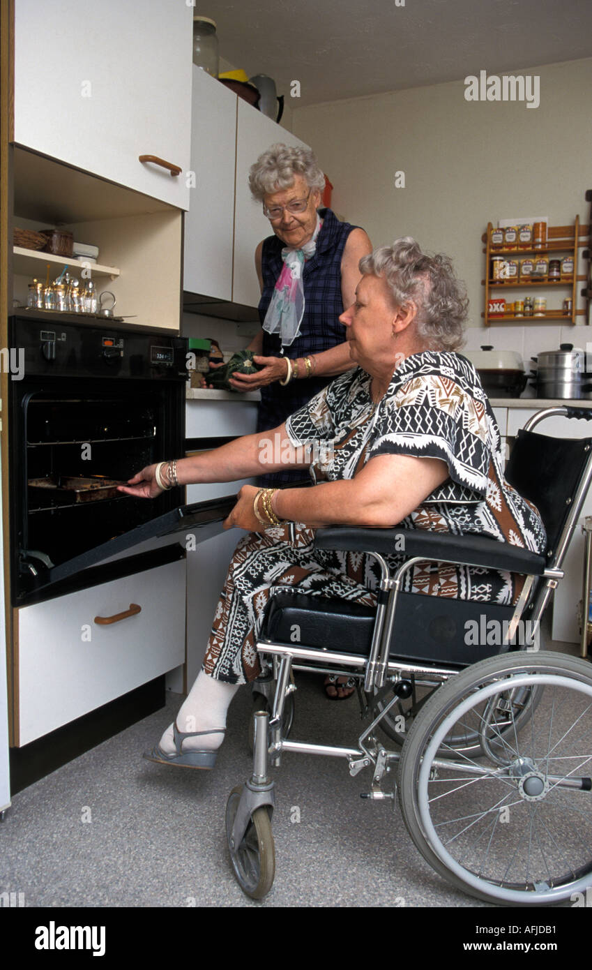 Frau im Rollstuhl kochen ihr Essen in Zweck gebaut Unterkunft mit niedrigen Niveau Ofen. Stockfoto