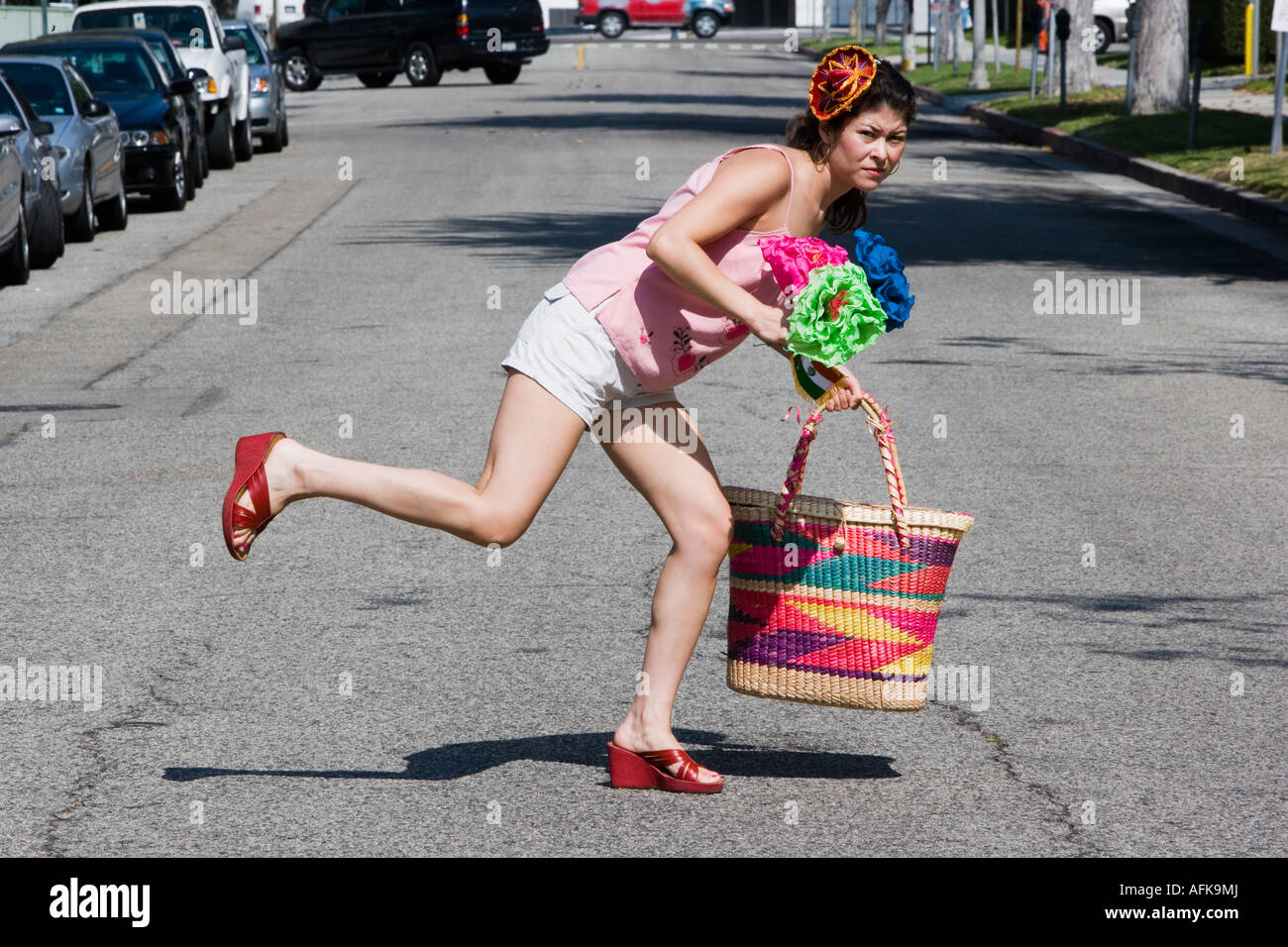 Frau über die Straße, Tragetasche und Blumen Stockfoto