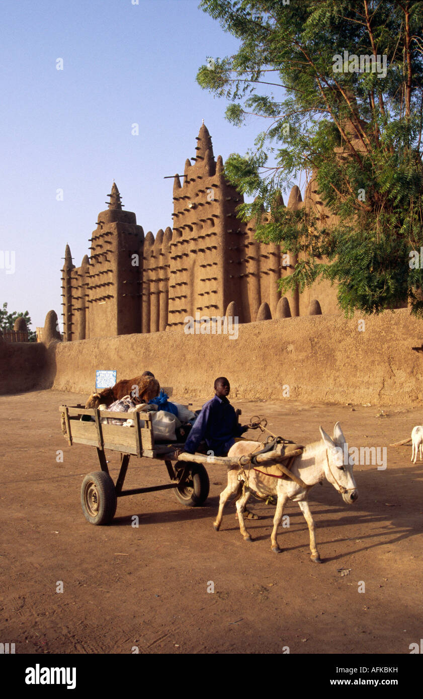 Ein Junge treibt seine Eselskarren vorbei an der großen Moschee in Djenné. Die Sahel-Stil-Moschee ist die weltweit größte Lehmziegel-Struktur. Stockfoto