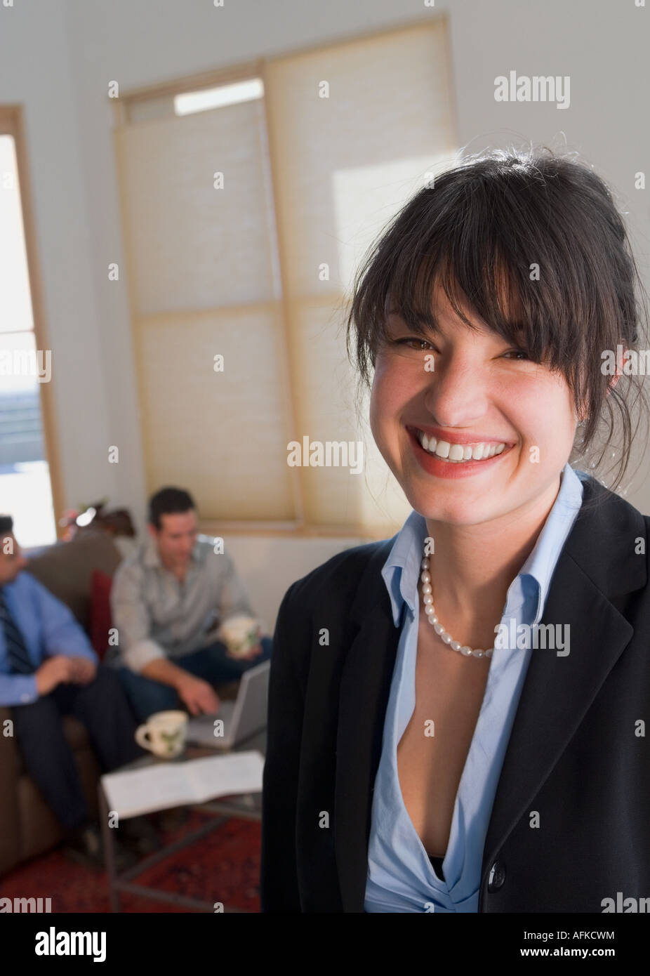 Porträt eines Geschäftsmannes lächelnd mit zwei Mitte Erwachsene Männer sitzen im Hintergrund Stockfoto