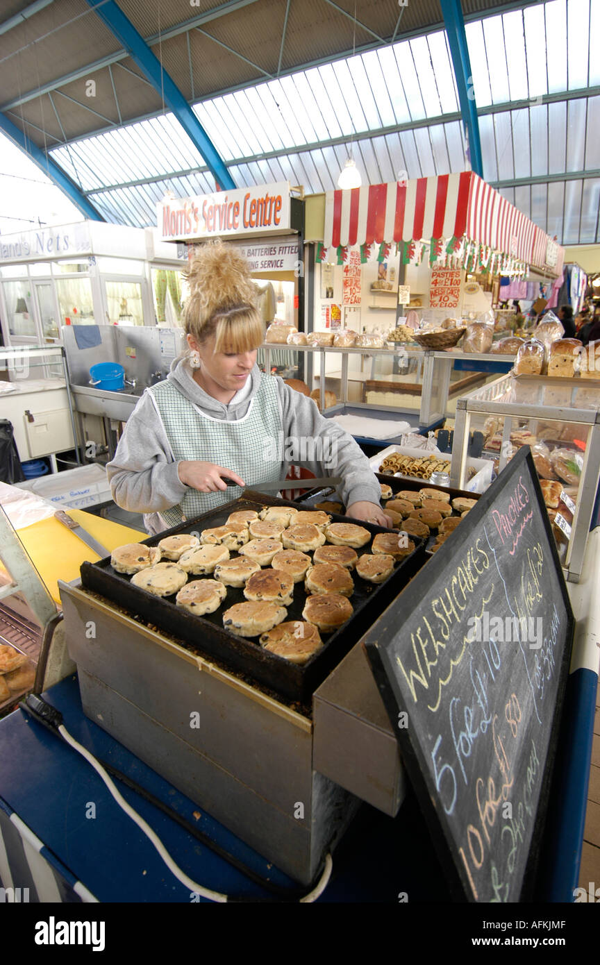 Frau, die einen Stapel von traditionellen Kochen stall Welsh Cakes (Drop Scones) auf ihr bei Markthalle Swansea, Wales, UK Stockfoto