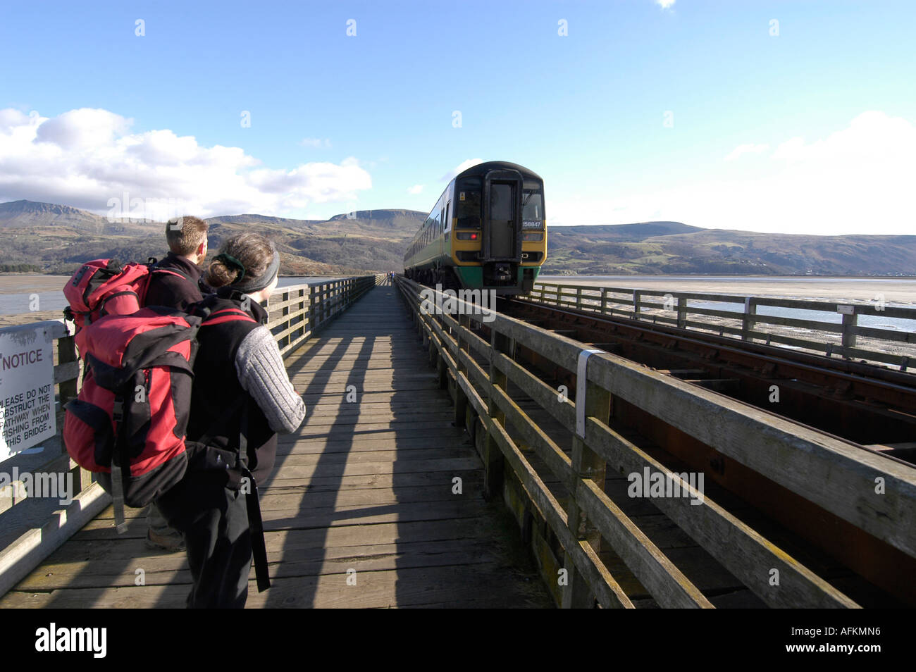 Familie wandern über die Schiene und Fuß Brücke über die Mündung des Mawddach Barmouth Snowdonia Gwynedd Nord-Wales, beobachten Zug Stockfoto