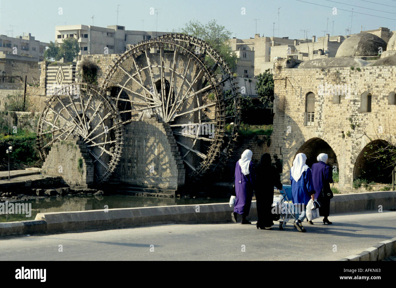 Gruppe von Frauen, die zu Fuß durch ein Wasserrad am Fluss Orontes, Hama, Syrien. Stockfoto