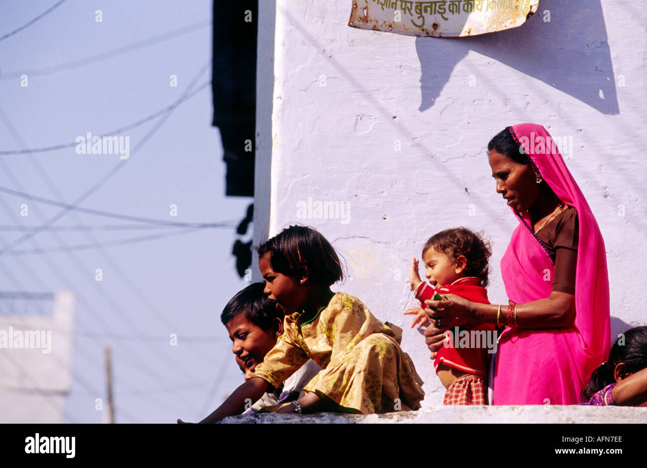 Indische Brahma Familie Mutter in einen hellen Sari und Kinder stehen draußen auf dem Balkon des sie Blau gestrichene Gebäude Stockfoto