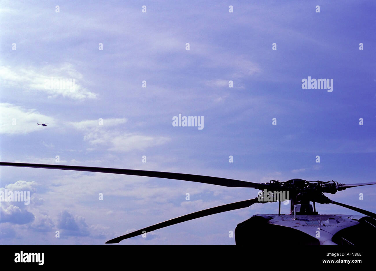 Rotorblätter im geliebten Teil des Rahmens gegen eine teilweise bewölkten blauen Himmel kleine Hubschrauber in der Ferne Stockfoto