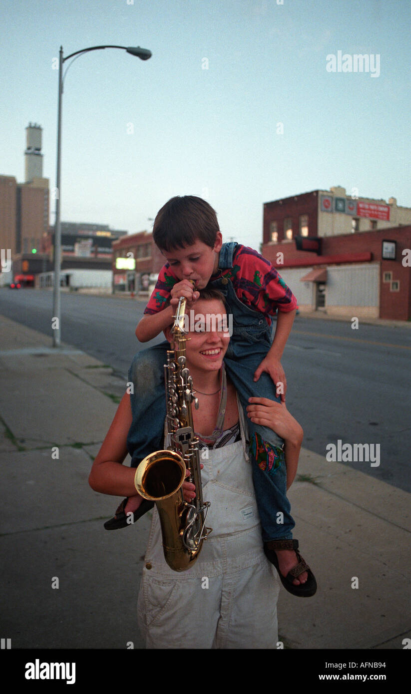Eine Travleling-Generation-X-Mädchen hält ein Saxophon außerhalb einer Gemeinde in der Innenstadt von Kansas City Missouri Stockfoto
