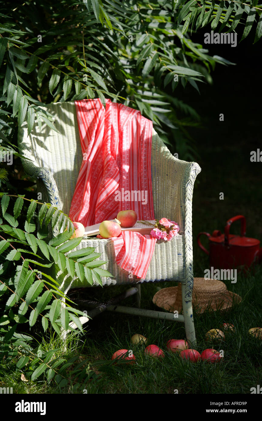 Nahaufnahme von rot gestreiften Wurf auf weißen Lloyd Loom Stuhl im Garten Stockfoto