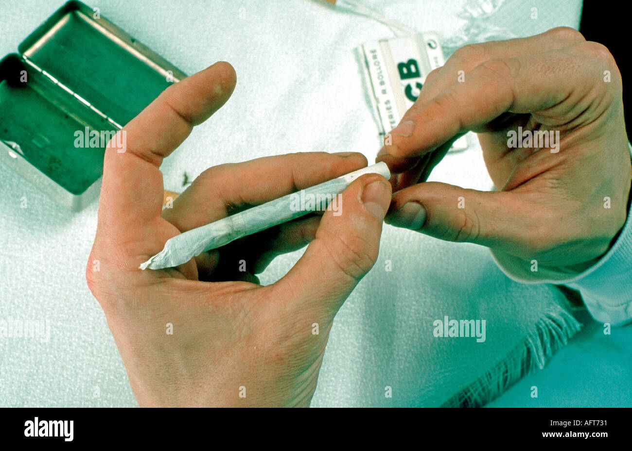 Männliche Hand, die Drogen hält: Haschisch wird mit Tabak in Zigaretten gerollt, raucht Unkraut Teenager Paris Stockfoto