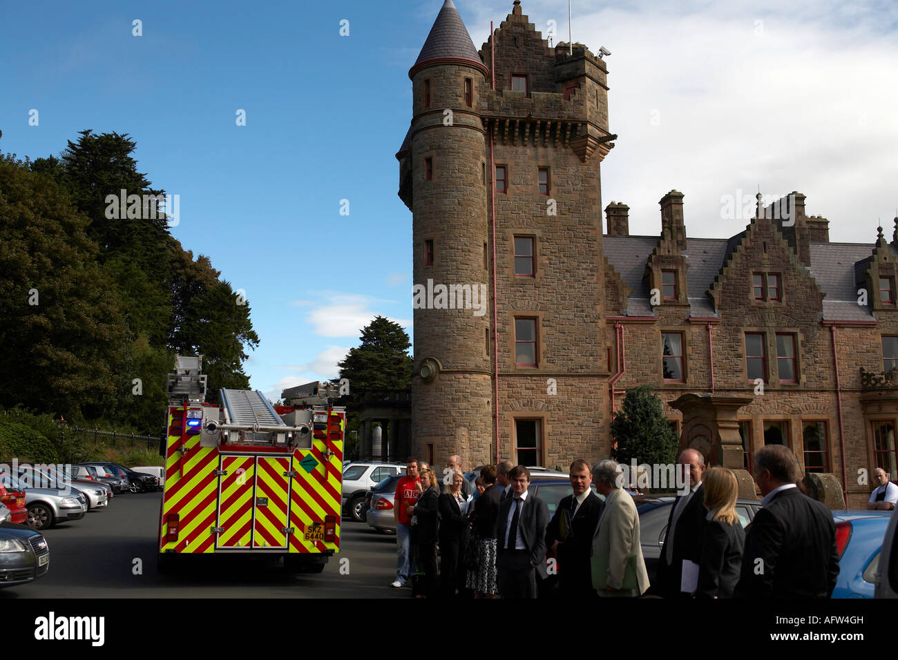 Gruppe von Geschäftsleuten stehen auf dem Parkplatz außerhalb Belfast Castle wegen Feueralarm als Feuerwehrauto kommt Stockfoto