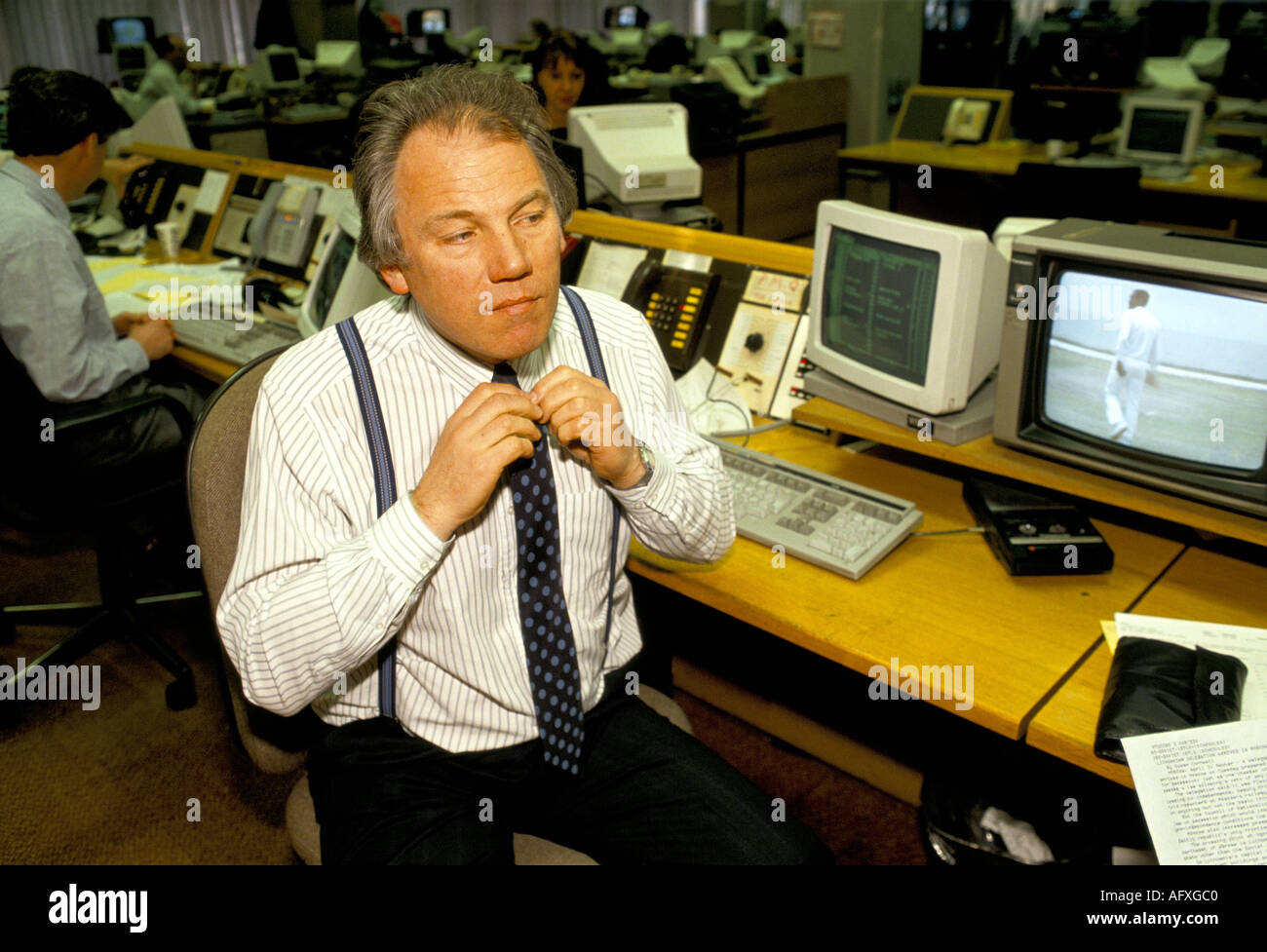Peter Sissons Porträt britischer Fernsehmoderator, der die Krawatte im Nachrichtenraum repariert. 1980er Jahre um 1985 London England Großbritannien HOMER SYKES Stockfoto