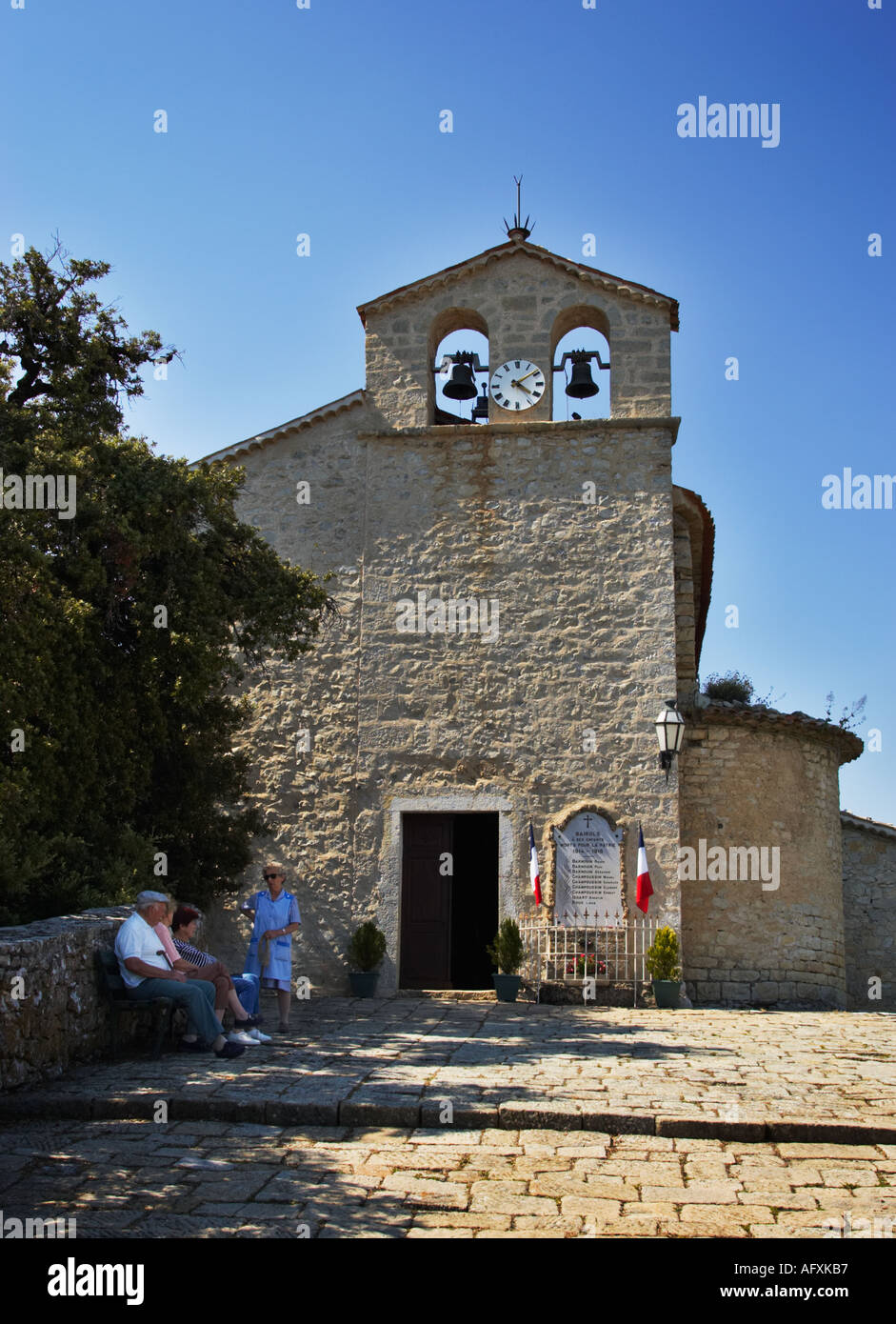 Einheimische sprechen außerhalb der Ste-Marguerite-Kirche in der Bergspitze Dorf von Bairols in den Alpes-Maritimes, Frankreich Stockfoto