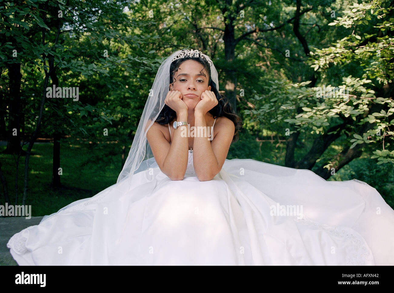 Eine junge Braut in einem schönen Brautkleid sitzen und schauen traurig und einsam Stockfoto