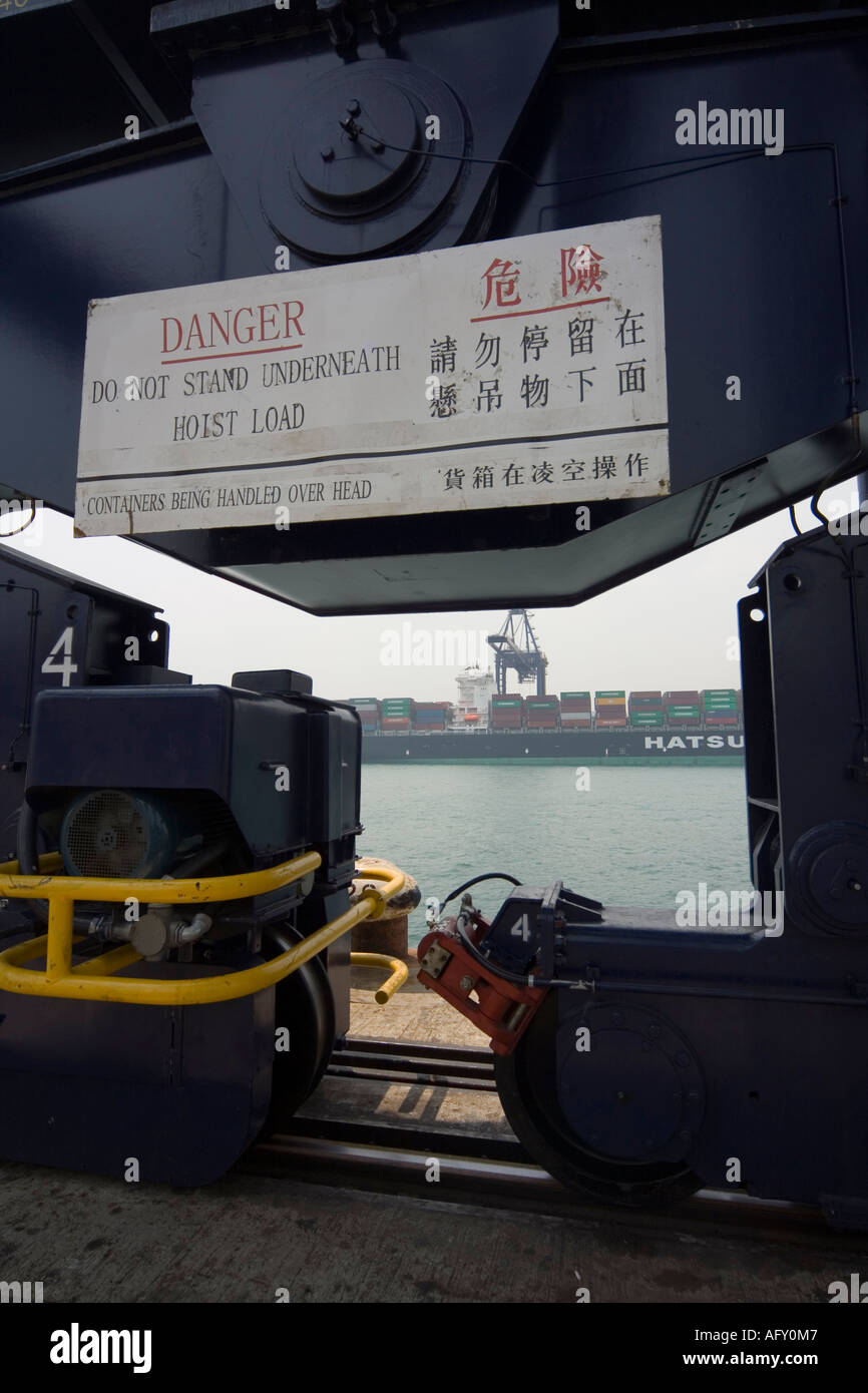 Zeichen auf Overhead-schweres Heben Kran Warnung der obenliegenden Gefahr mit Blick auf massive Containerschiff im Hintergrund Kwai Chung Port Stockfoto