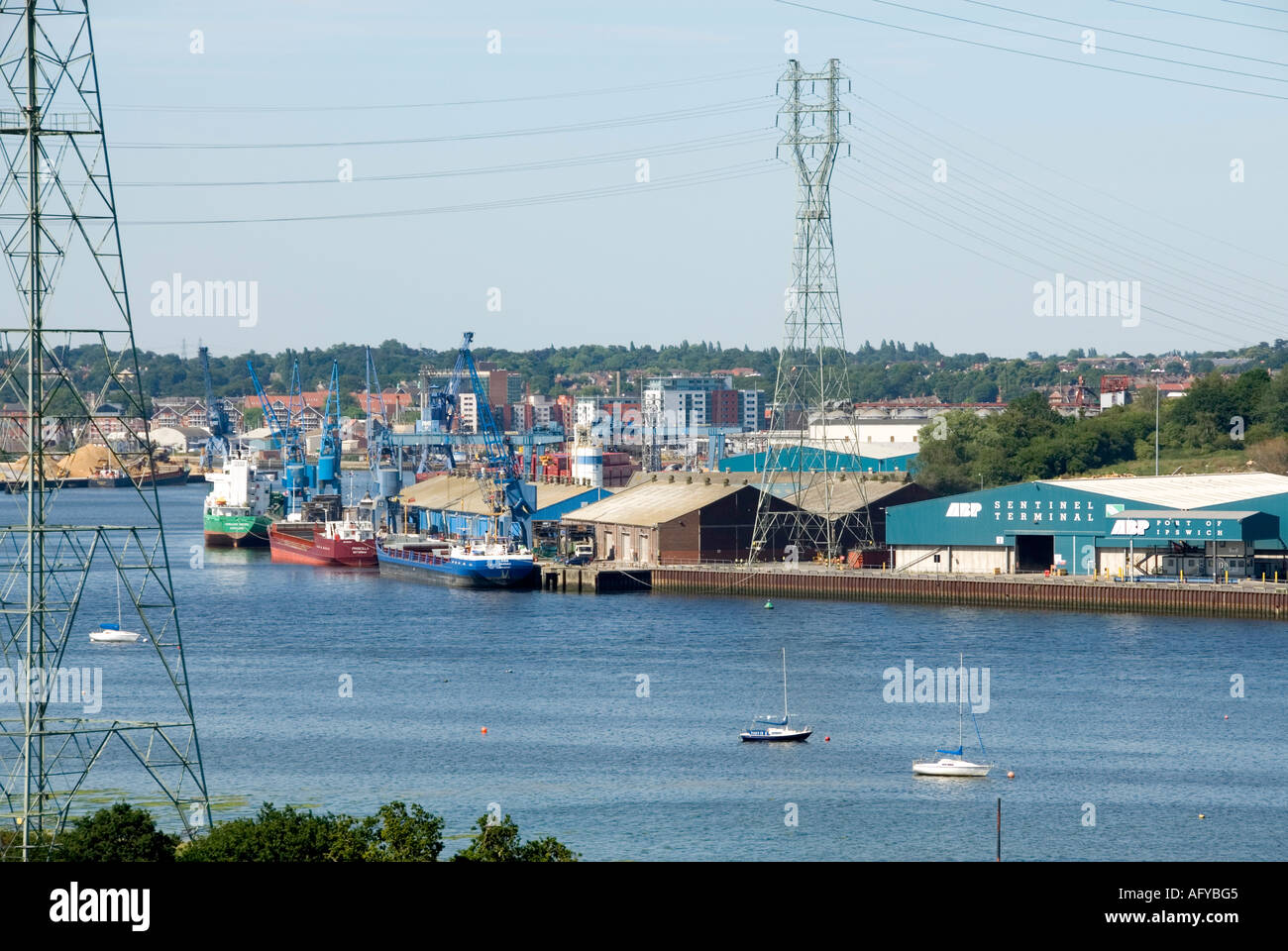 Die Schiffe legen in Lagern am Flussufer der Ipswich Docks unterhalb von National Grid an Hochspannungsmasten und Kabeln an, die den Fluss Orwell Suffolk UK überspannen Stockfoto