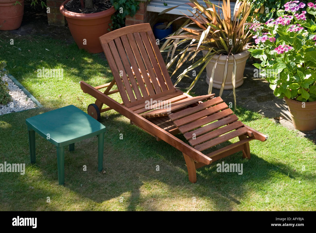Das entfernte Kissen für Liegestühle im Garten im Sommer zeigt, dass im Vergleich zum benachbarten Little Plastic able England UK eine umfangreiche Verwendung von Hartholzrohstoffen vorliegt Stockfoto
