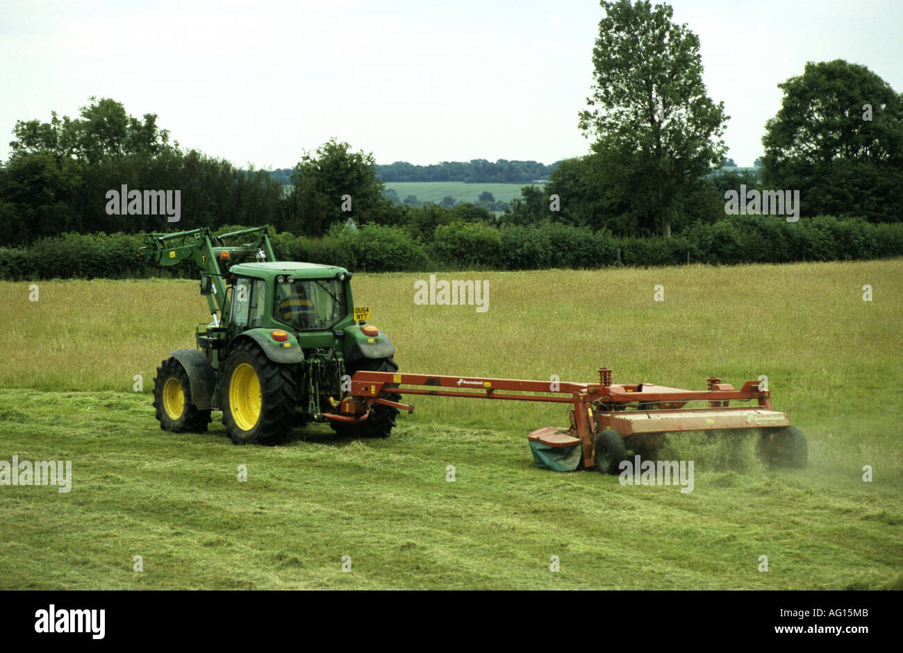 John Deere Traktor schneiden Heu-Feld im Sommer, Northamptonshire, England, UK Stockfoto