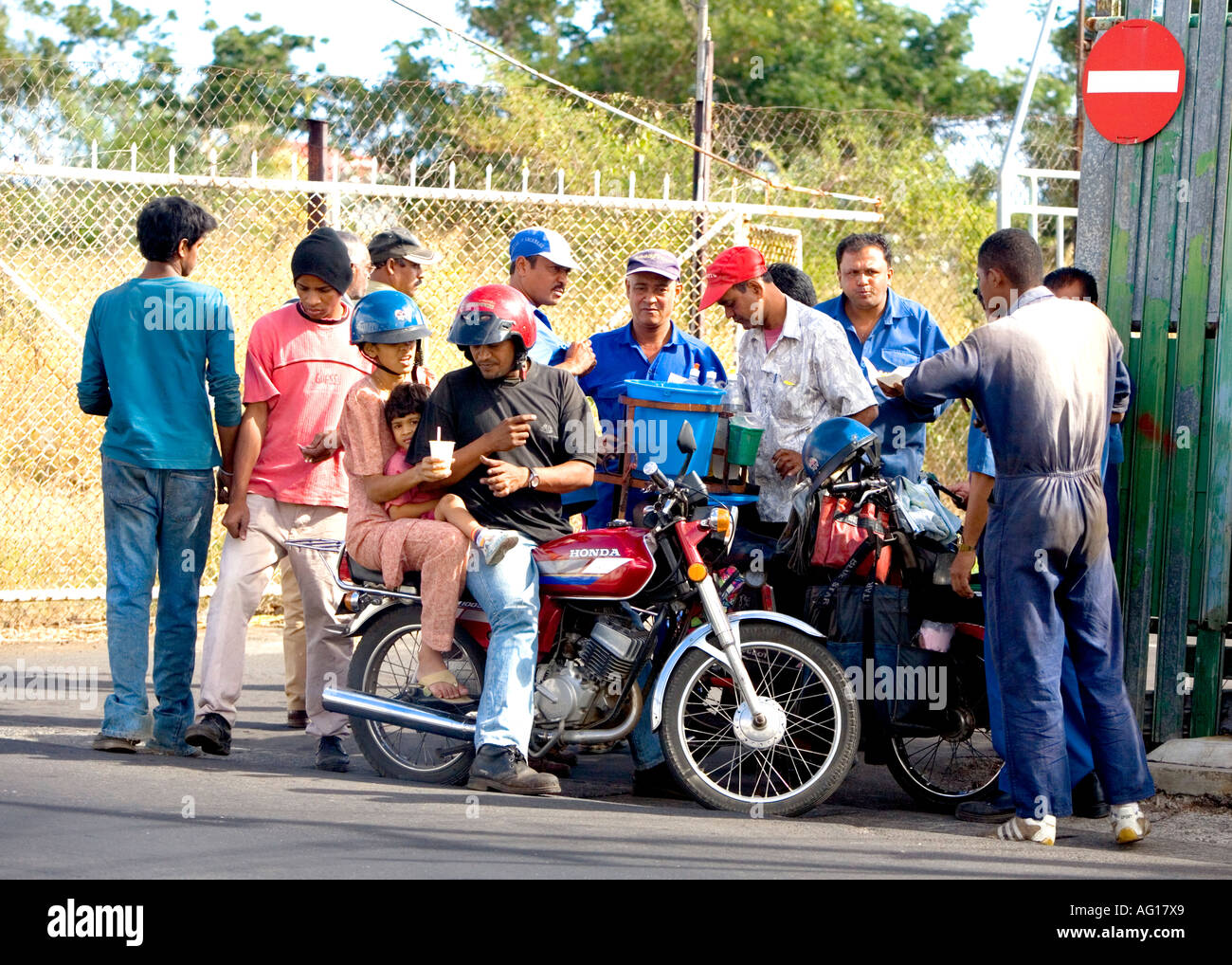 Fabrikarbeiter und vorbeifahrenden Familie auf dem Motorrad belagern Dhal Puri Partner - Mauritius Stockfoto