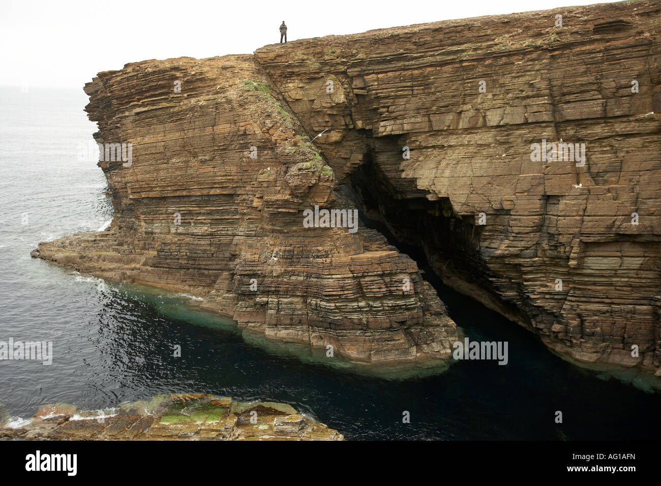 Einsame Gestalt steht über einen natürlichen Bogen Garthna Geo Bucht Yesnaby Orkney Scotland UK Stockfoto