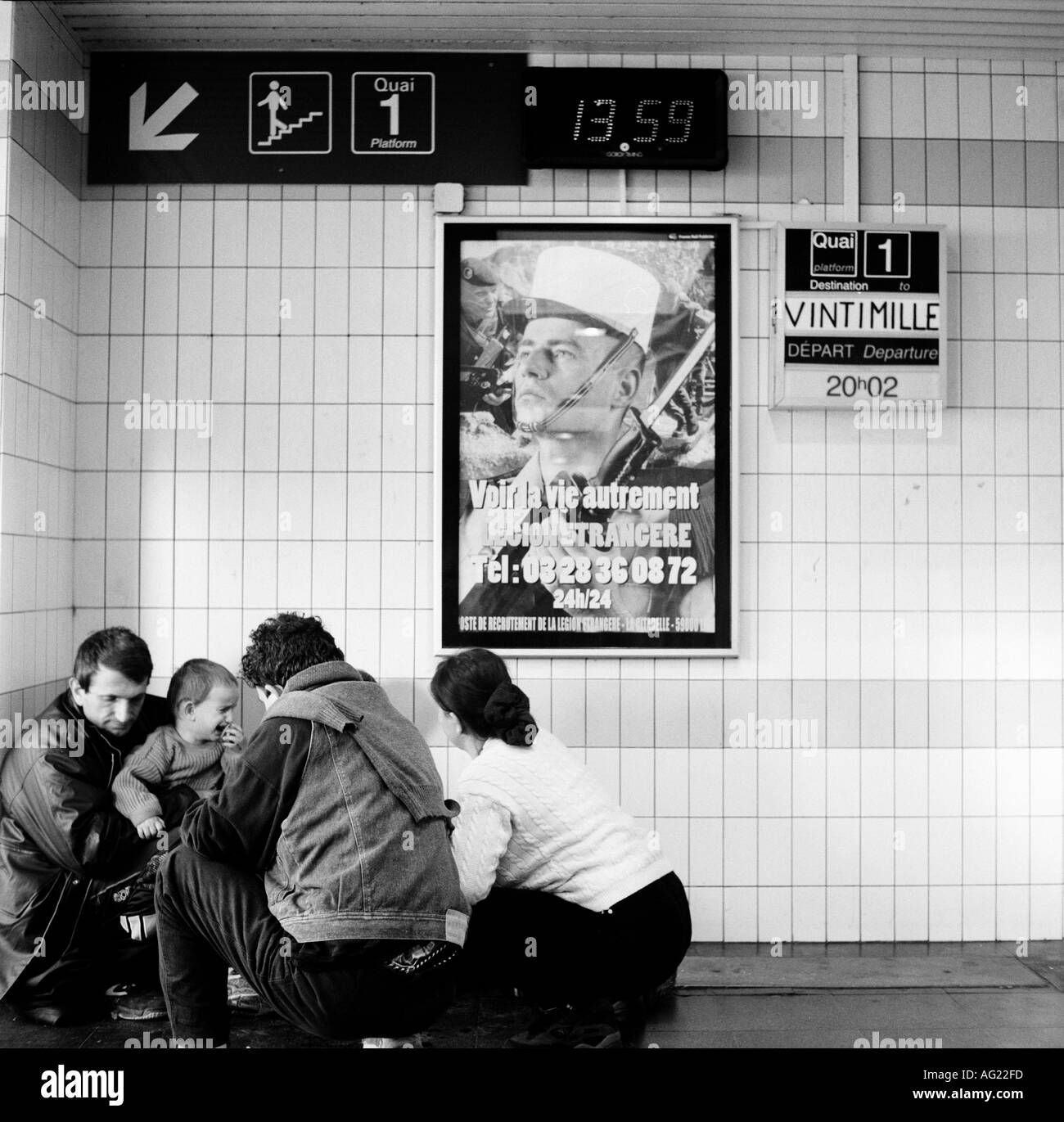 Asylbewerber aus dem Kosovo warten Sie unten ein Plakat der französischen Fremdenlegion bei Calais Bahnhof, Calais, Frankreich. 2000. Stockfoto