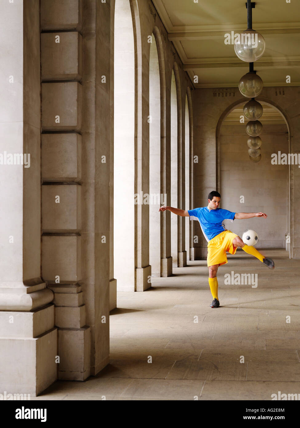 Fußball-Spieler treten Ball im Portikus Stockfoto