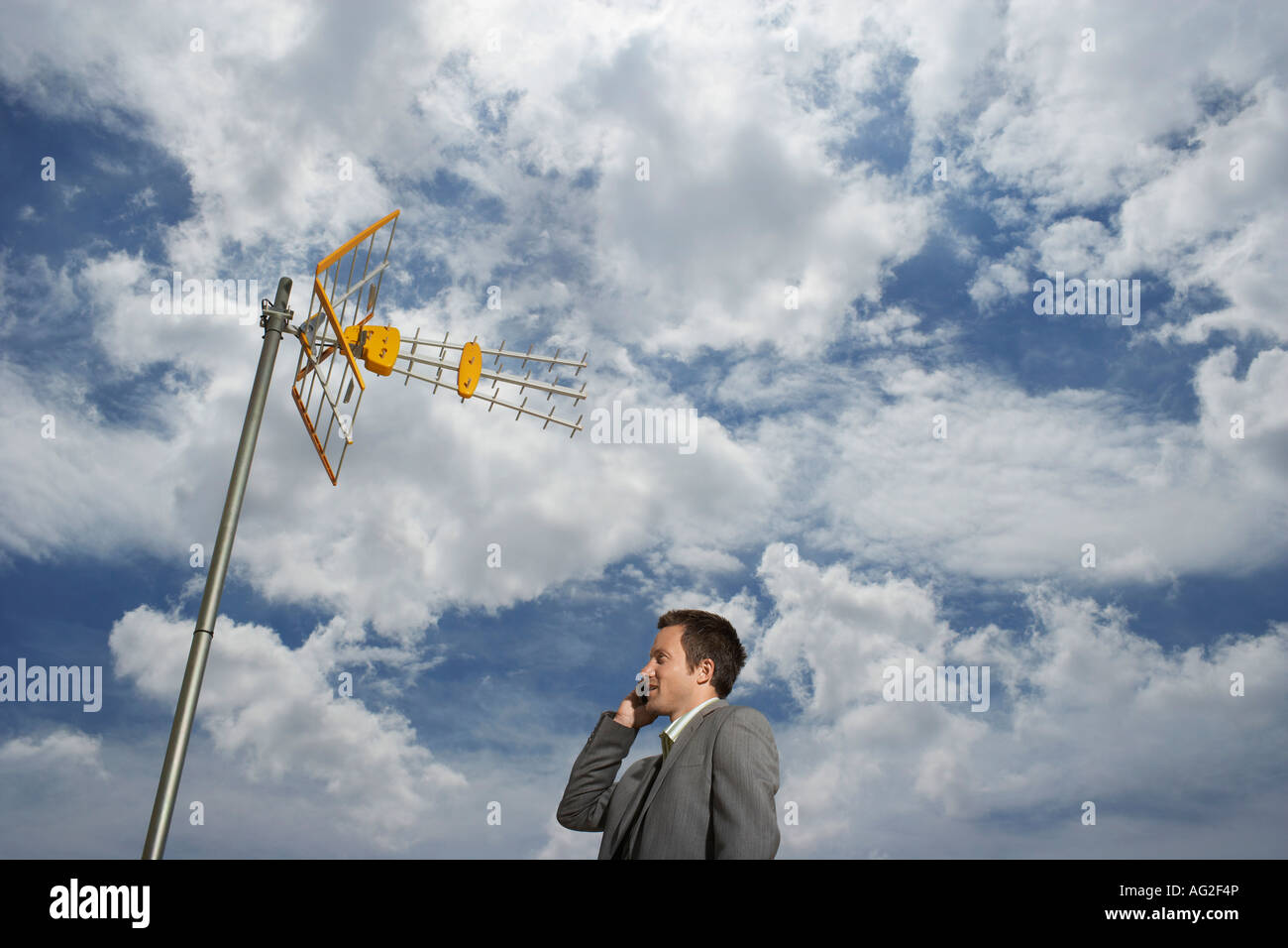 Business-Mann mit Handy unter Sat-Turm Stockfoto