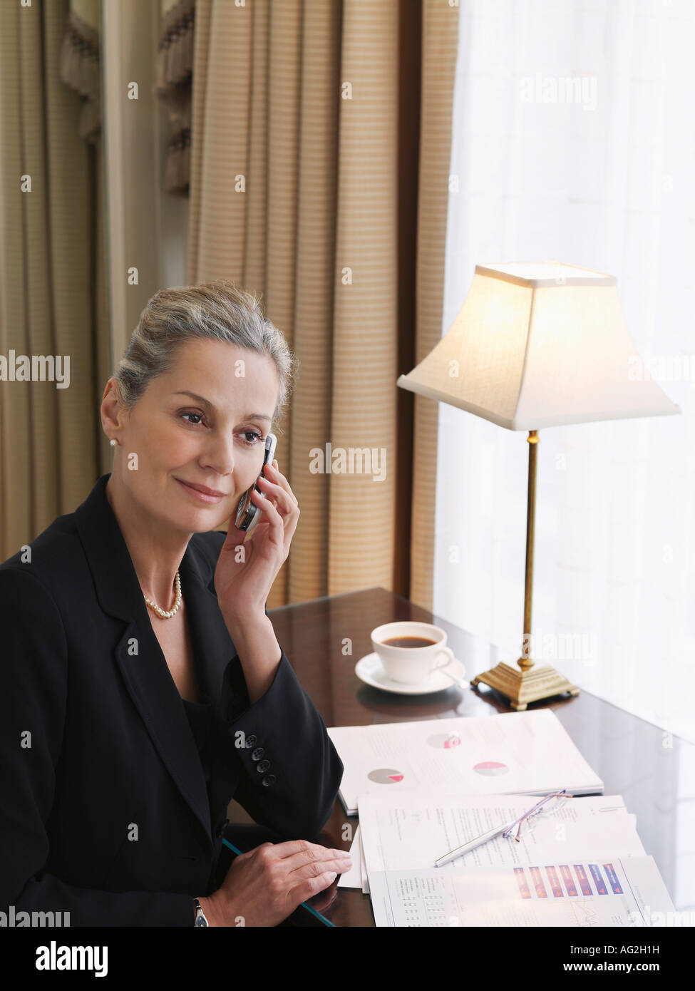 Business-Frau mit Handy sitzen am Schreibtisch, erhöht, Ansicht Stockfoto