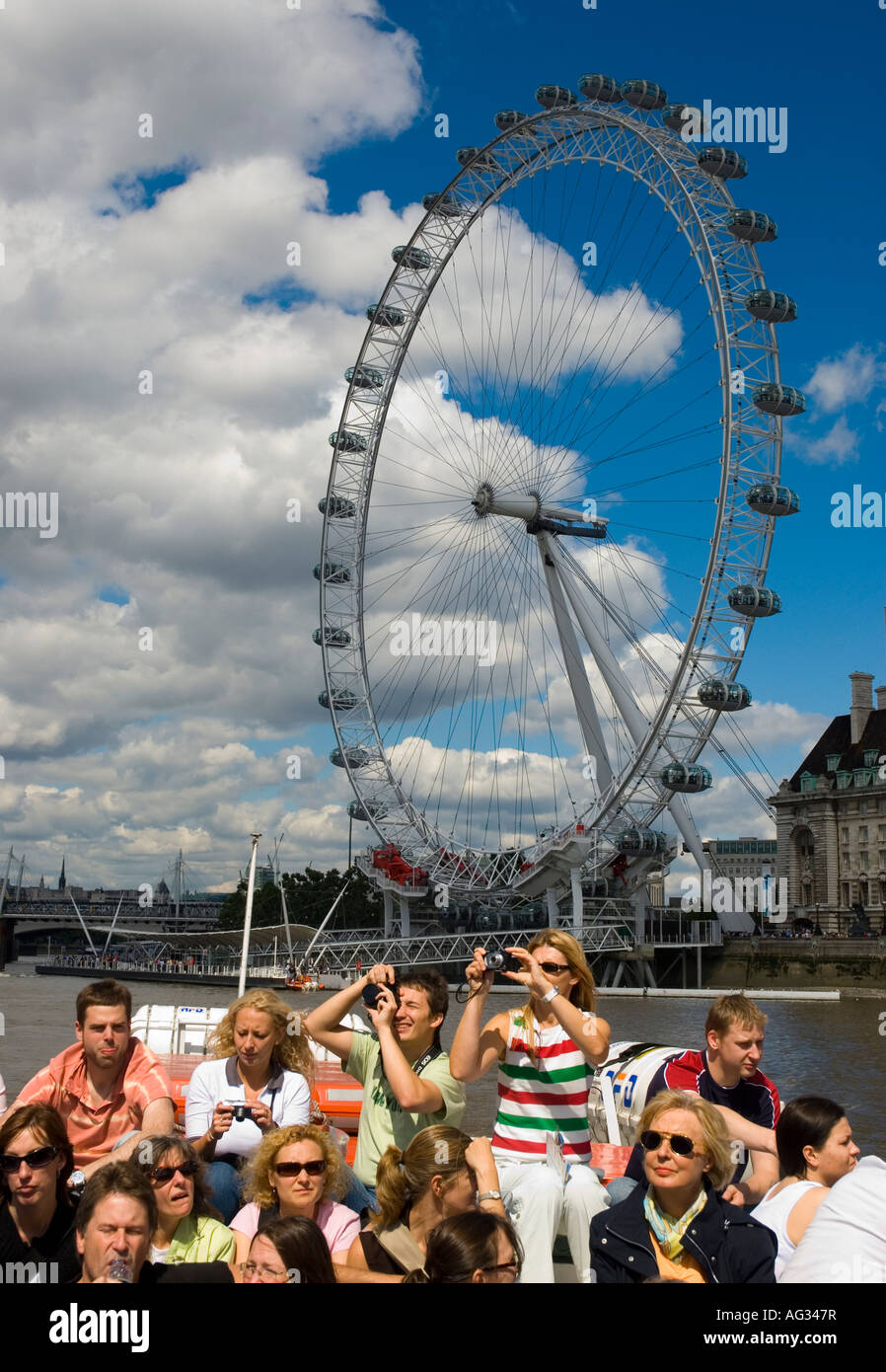 Leute betrachten den Houses of Parliament von einer Bootsfahrt auf der Themse mit dem London Eye im Hintergrund Stockfoto