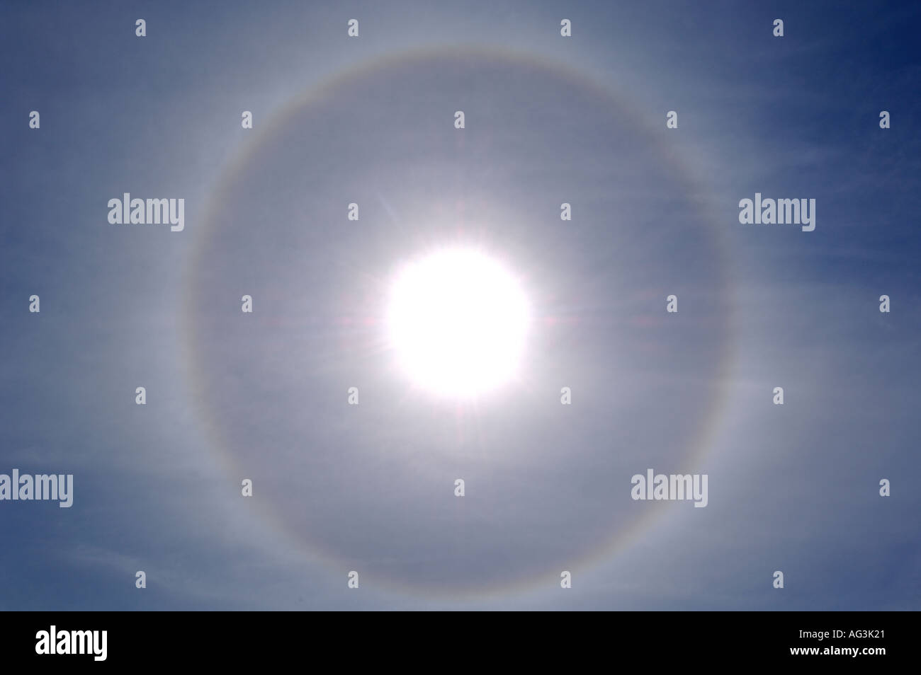 Solar Halo bildet hellen Kreis des gebrochenen Lichts in Eiskristalle um Sonne und blauer Himmel und Wolken Stockfoto