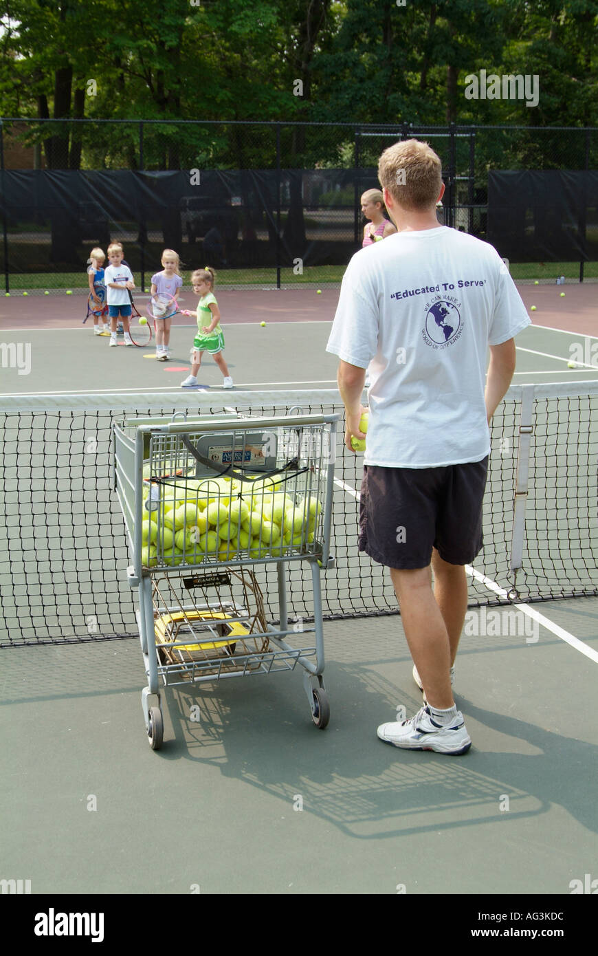 4 und 5 jährige Kinder nehmen Gruppe Tennis Lektionen gelehrt von College-Studenten auf einen öffentlichen Tennisplatz Stockfoto