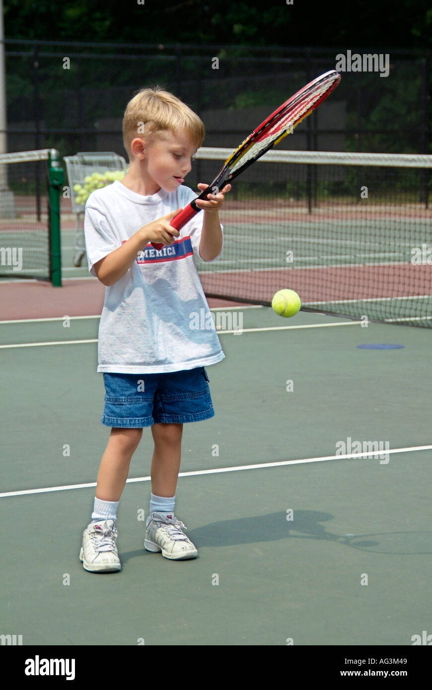 4 und 5 jährige Kinder nehmen Gruppe Tennis Lektionen gelehrt von College-Studenten auf einen öffentlichen Tennisplatz Stockfoto