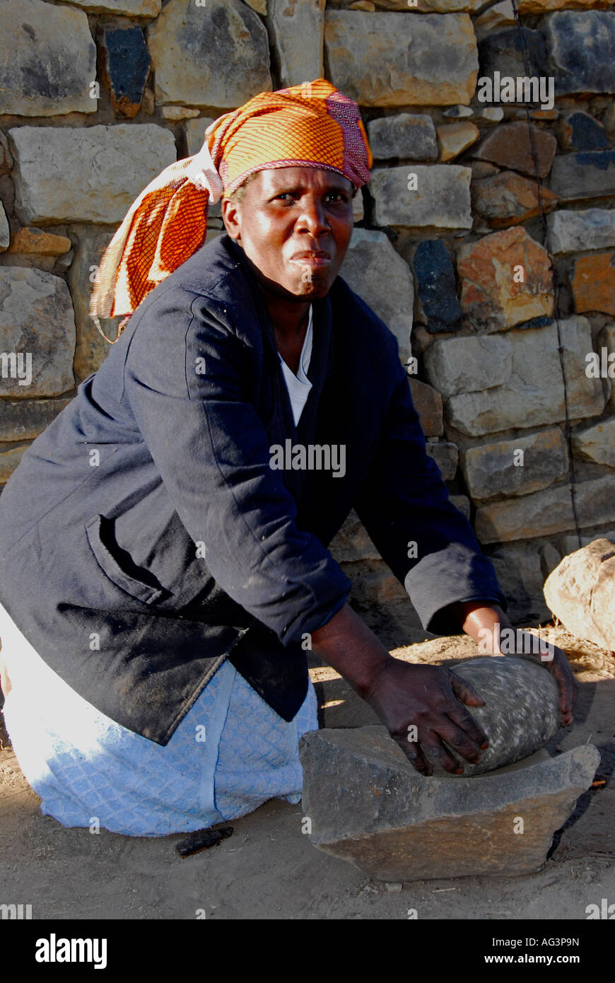 Basotho Frau Schleifen Mais/Mais die traditionelle Art in hohlen Felsen, Lesotho, Afrika Stockfoto