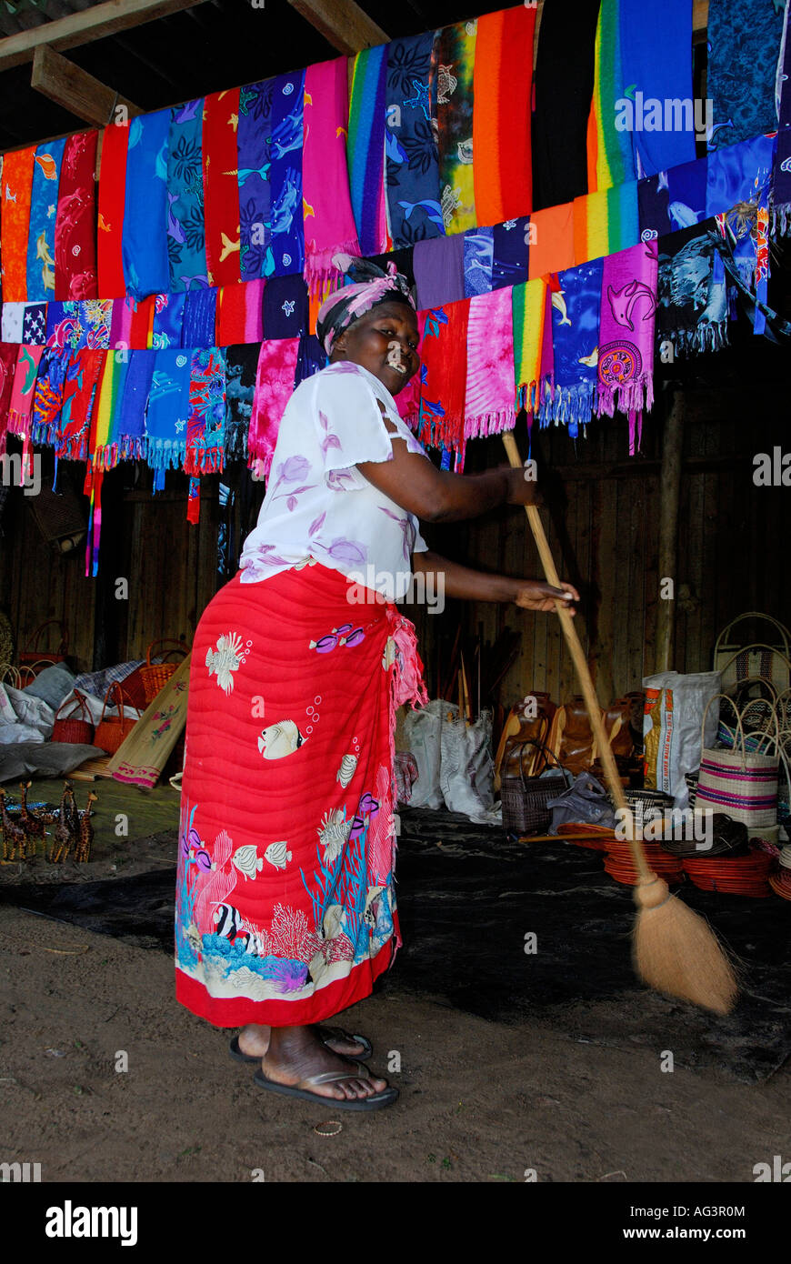 Zulu Frau fegt Stall mit bunten Kleidung im Hintergrund Stockfoto