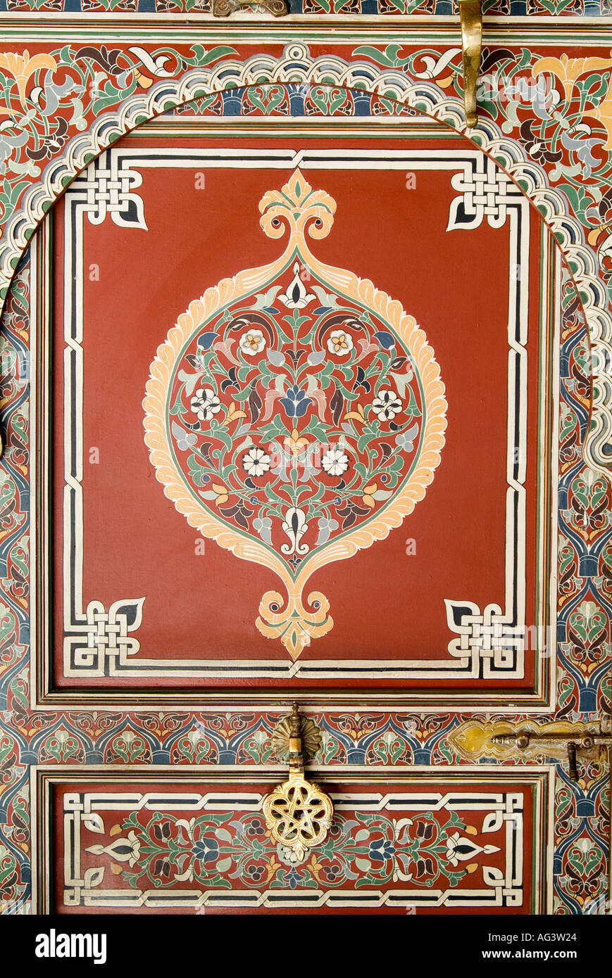 Marrakesch, Marokko. Detail der eingelegten gemalten verzierten Tür mit Messing Knopf. Stockfoto