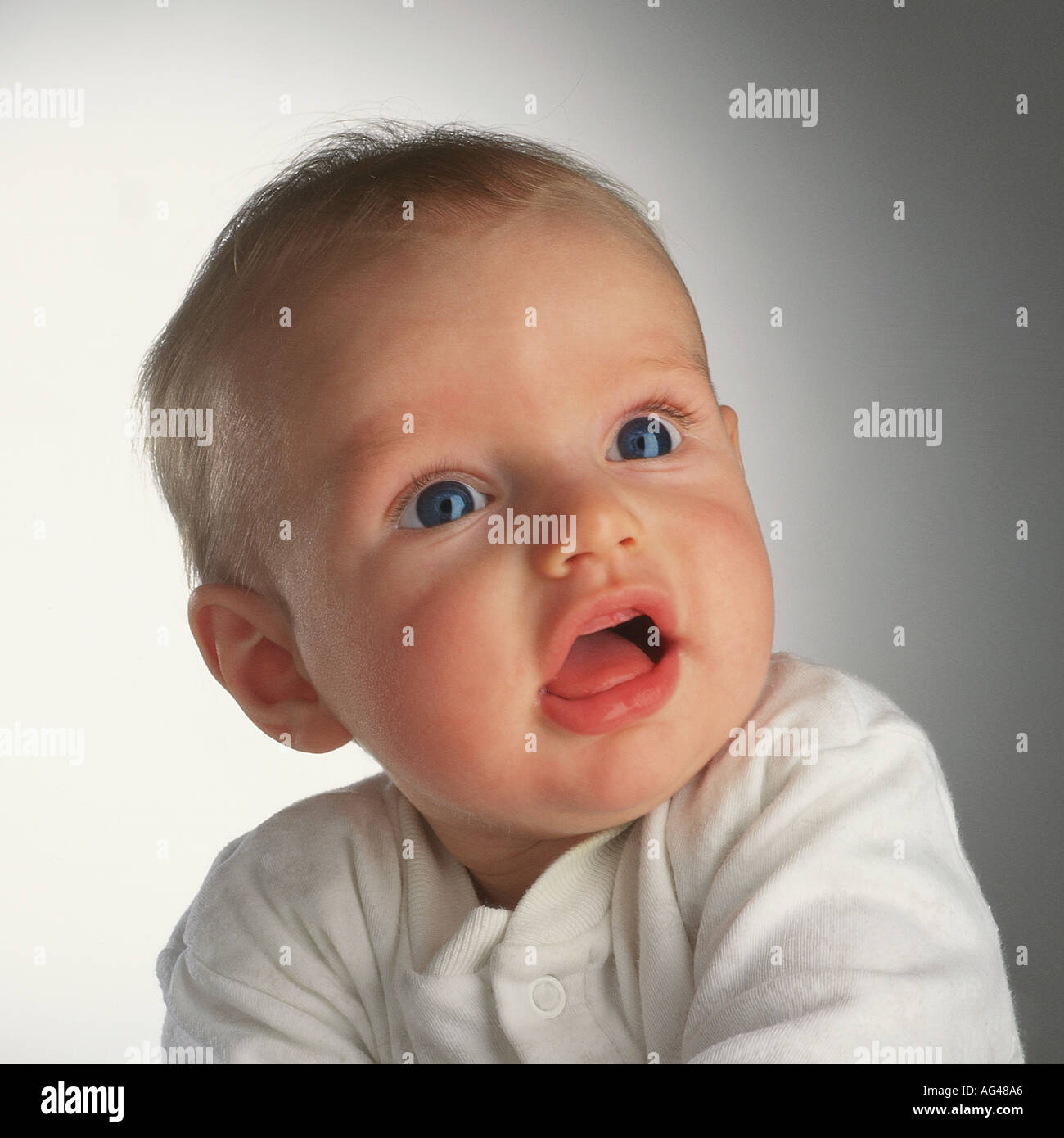Sechs Monate alter Baby-Junge, der aufschaut. Keine Zähne. Große Augen. Studio-Aufnahme, einfacher Hintergrund. Stockfoto